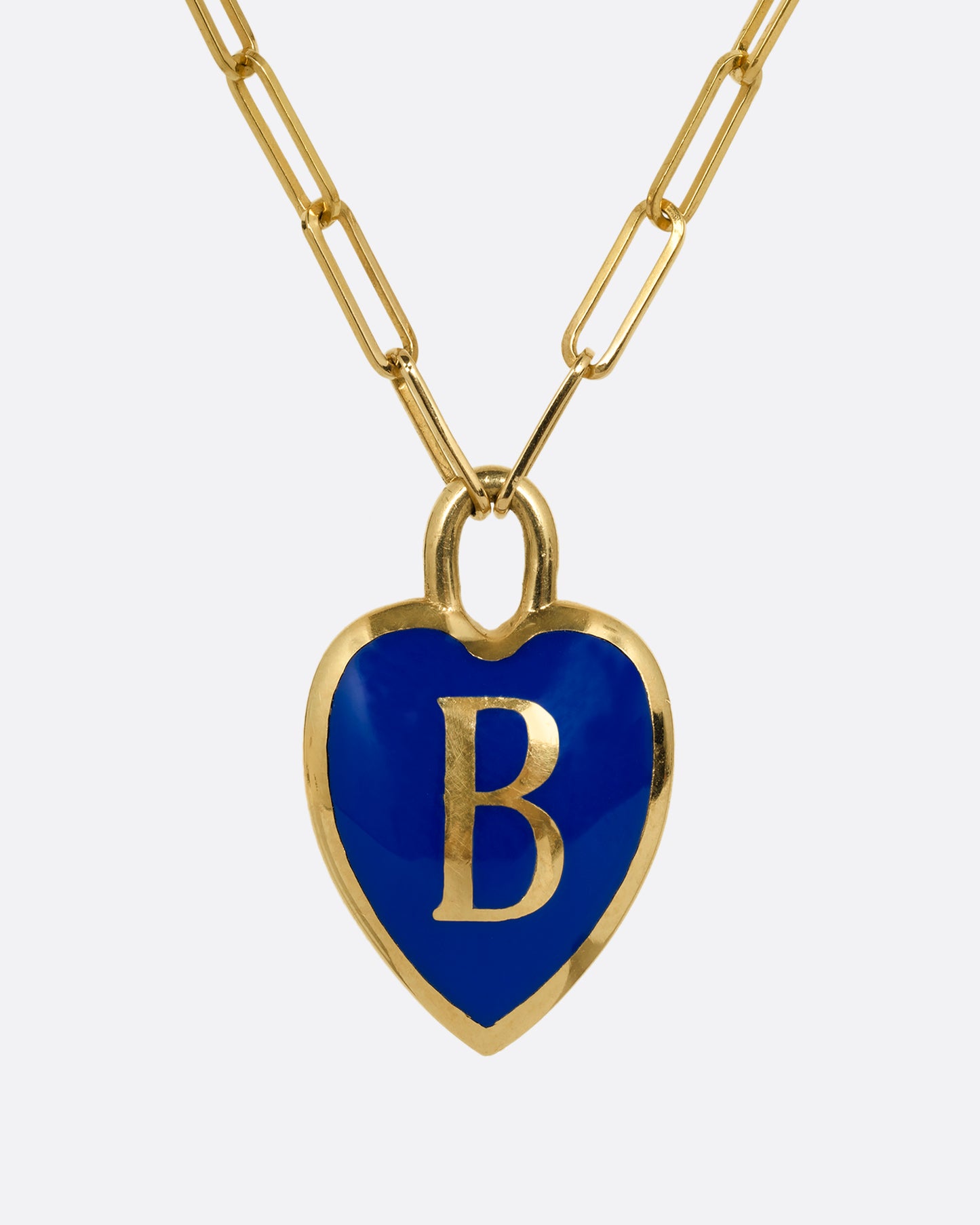 A yellow gold paperclip chain necklace with a blue enamel heart shaped B pendant. Shown from the front.