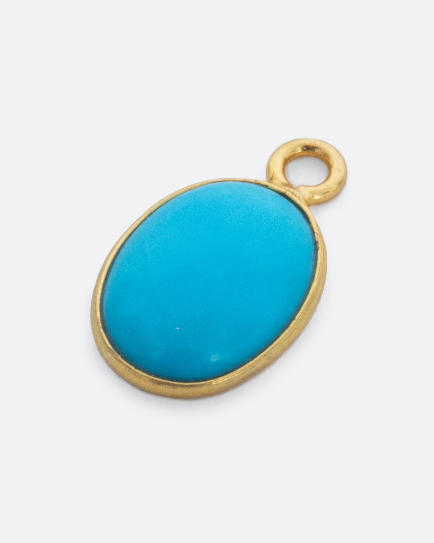 A Sleeping Beauty Turquoise dangle set in yellow gold with a yellow gold bail. Shown lying flat from the front.