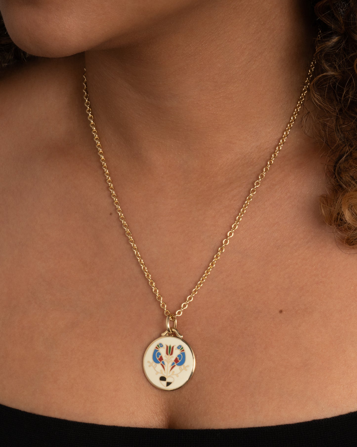 A yellow gold pendant on a cable chain. Shown worn around the neck.