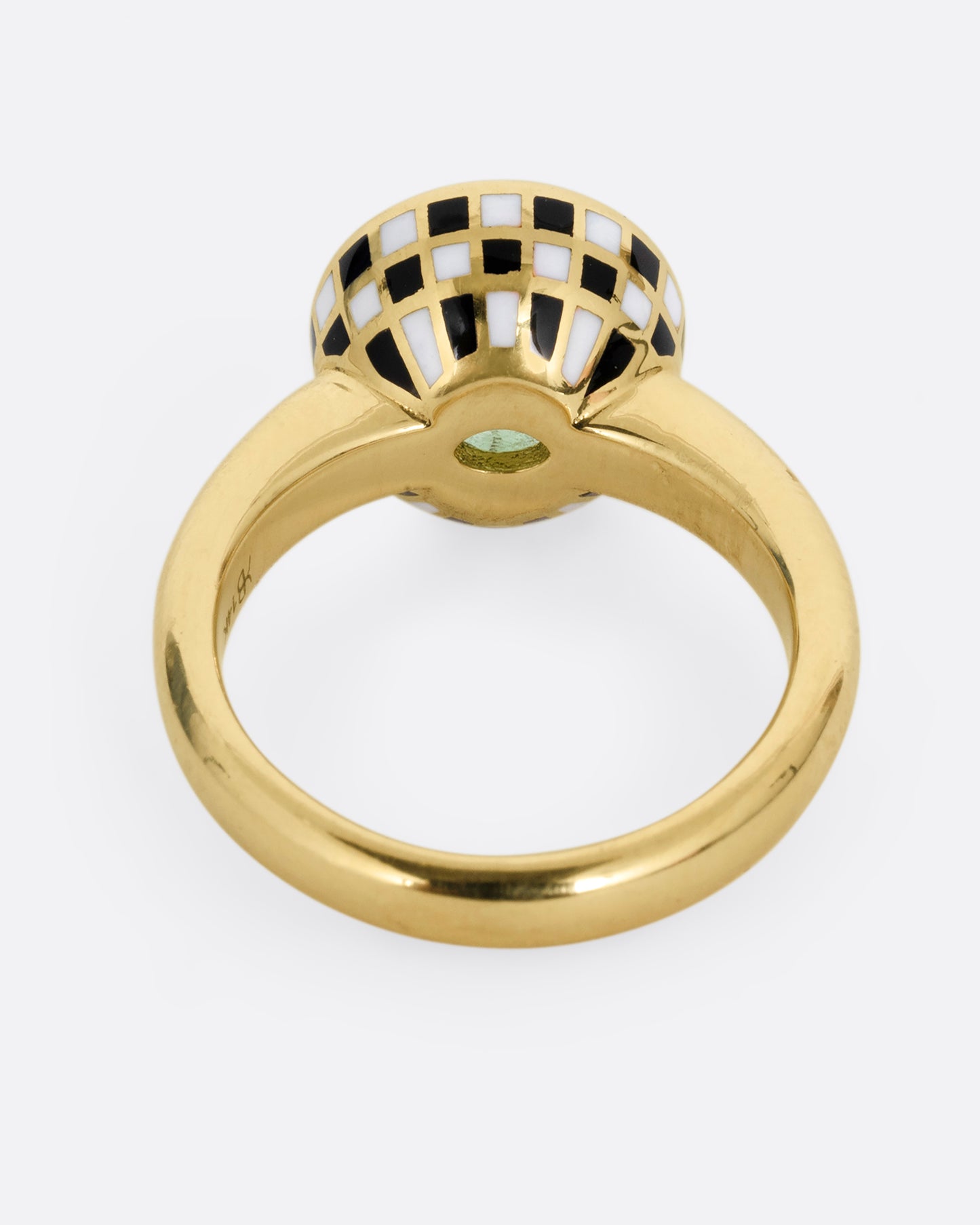 A yellow gold ring with an enamel black and white checkerboard pattern framing a green tourmaline. Shown from the back.