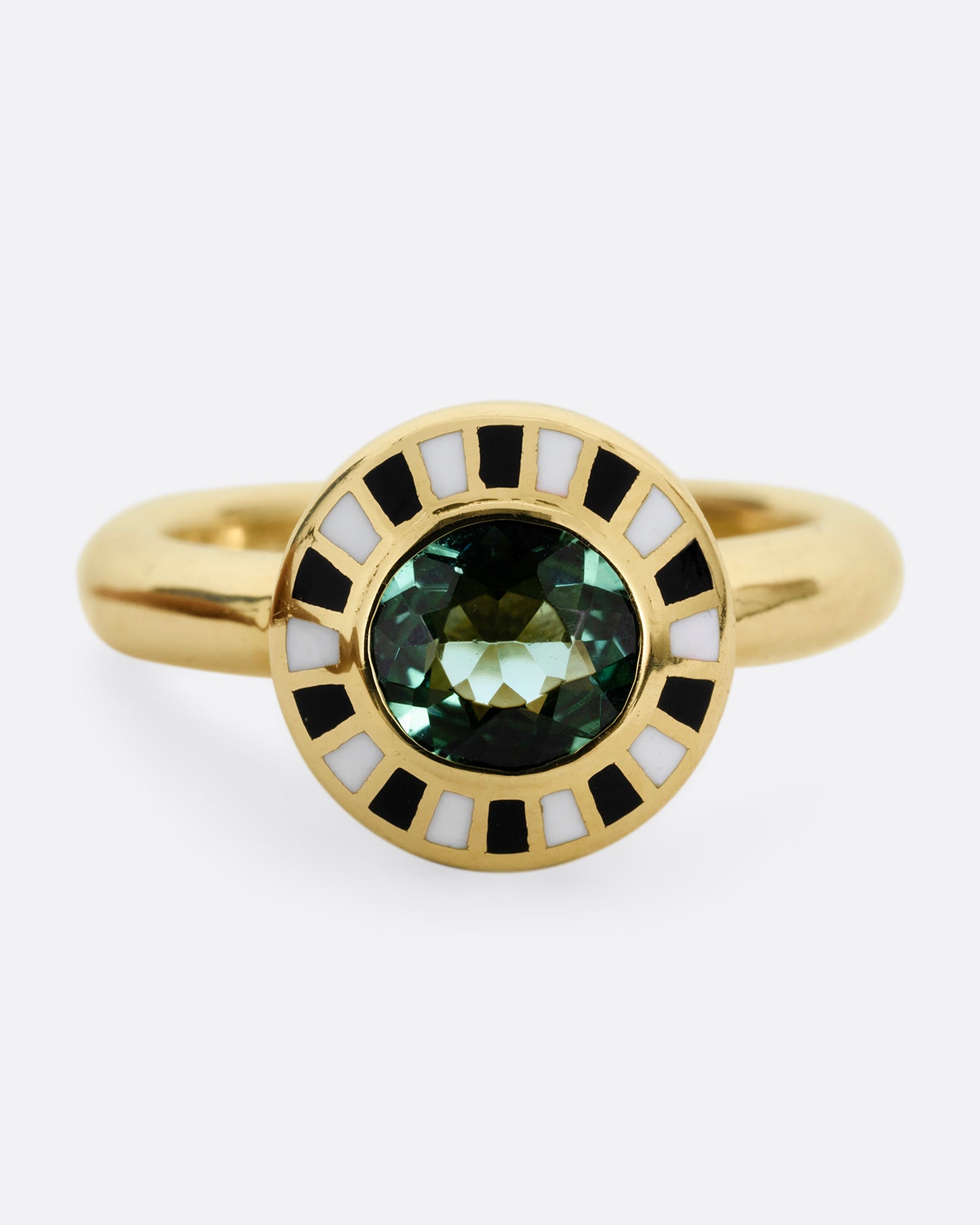 A yellow gold ring with an enamel black and white checkerboard pattern framing a green tourmaline. Shown from the front.