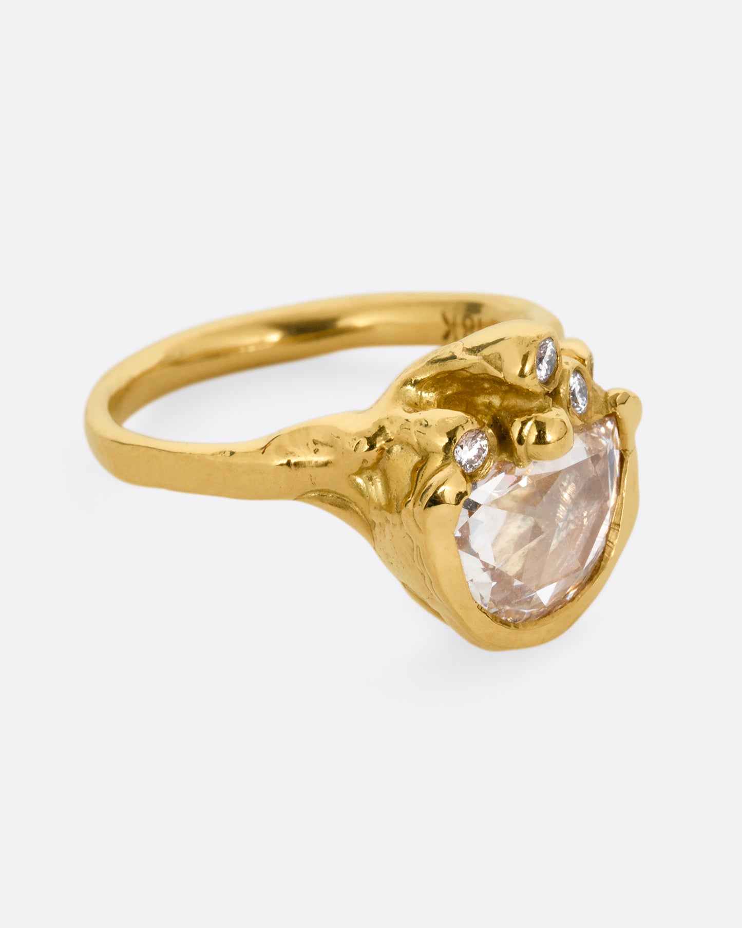 A yellow gold ring with a central rose cut diamond half moon and bezel set diamond accents on top of the flat side. Shown from the side.
