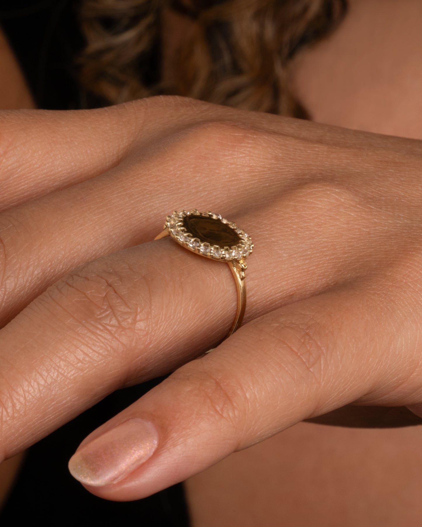 A 14k gold circle ring with a white diamond halo. Shown worn on a hand.