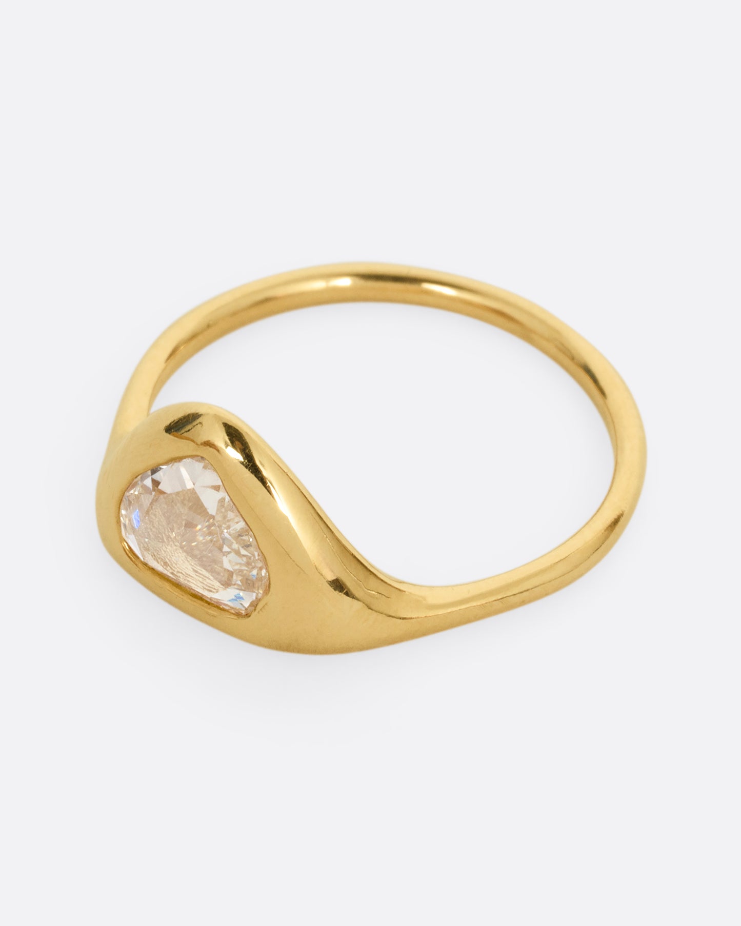 A yellow gold ring with a triangular rose cut diamond. Shown from the side.