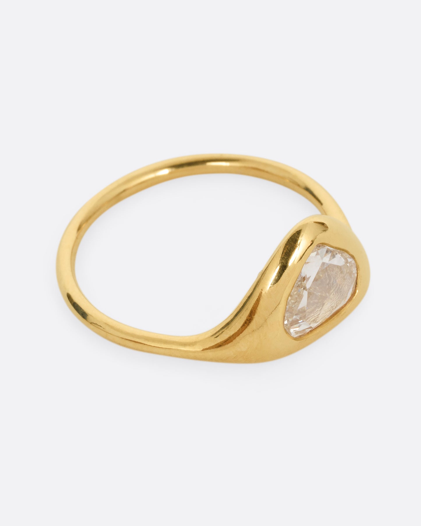 A yellow gold ring with a triangular rose cut diamond. Shown from the side.