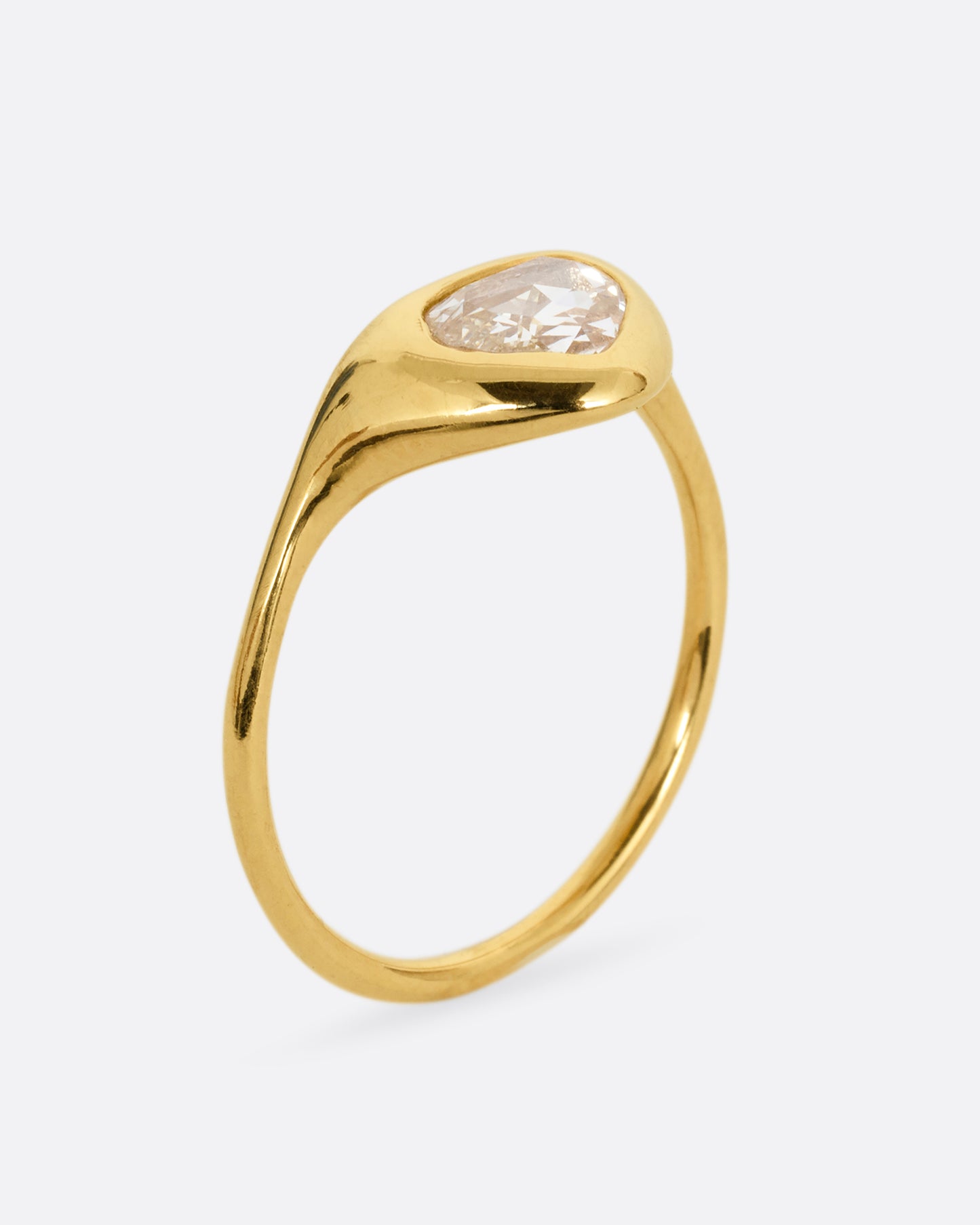 A yellow gold ring with a triangular rose cut diamond. Shown from the side standing up.