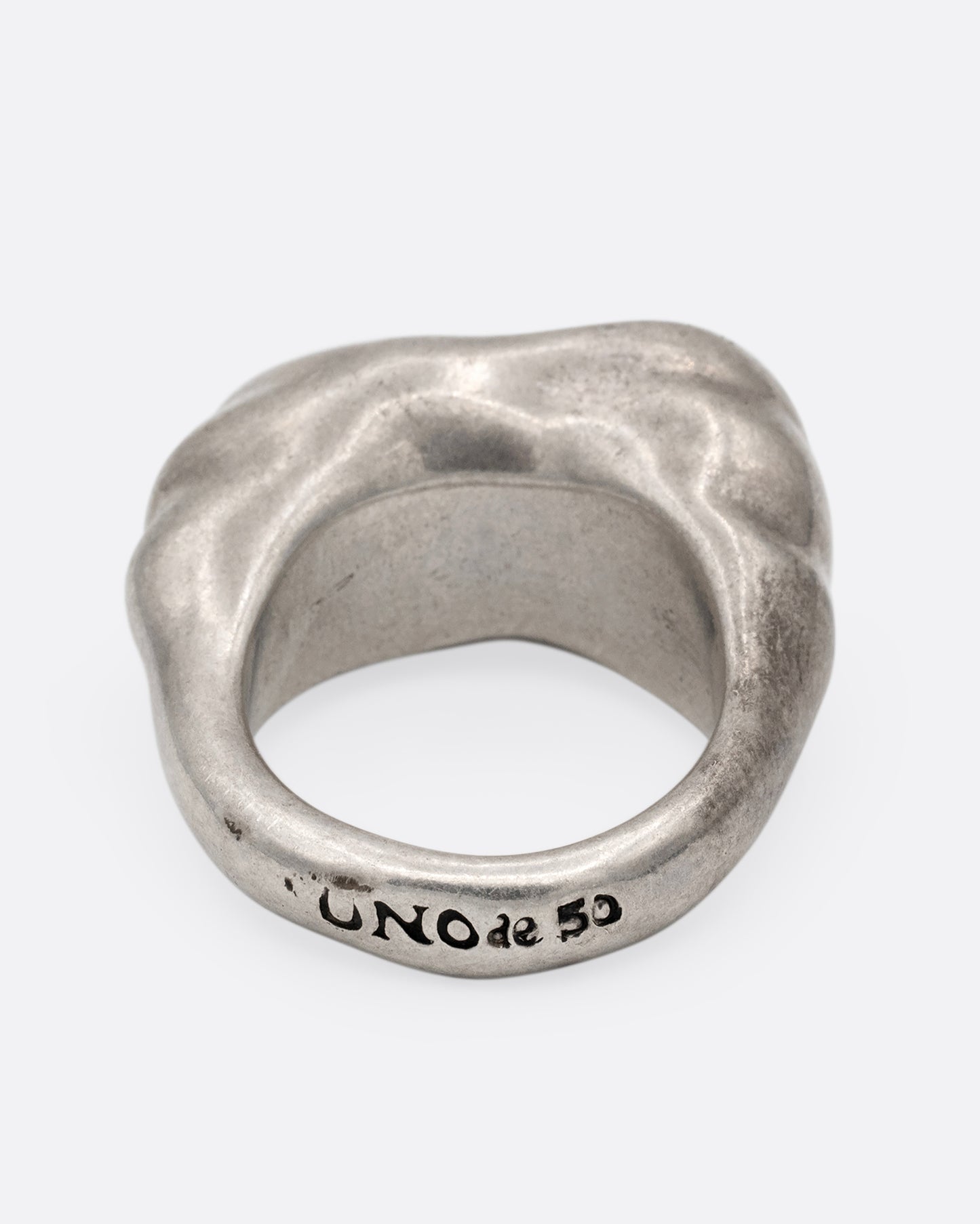 A silver ring with a cluster of free moving hoops nestled into its towering face. Shown from the back.