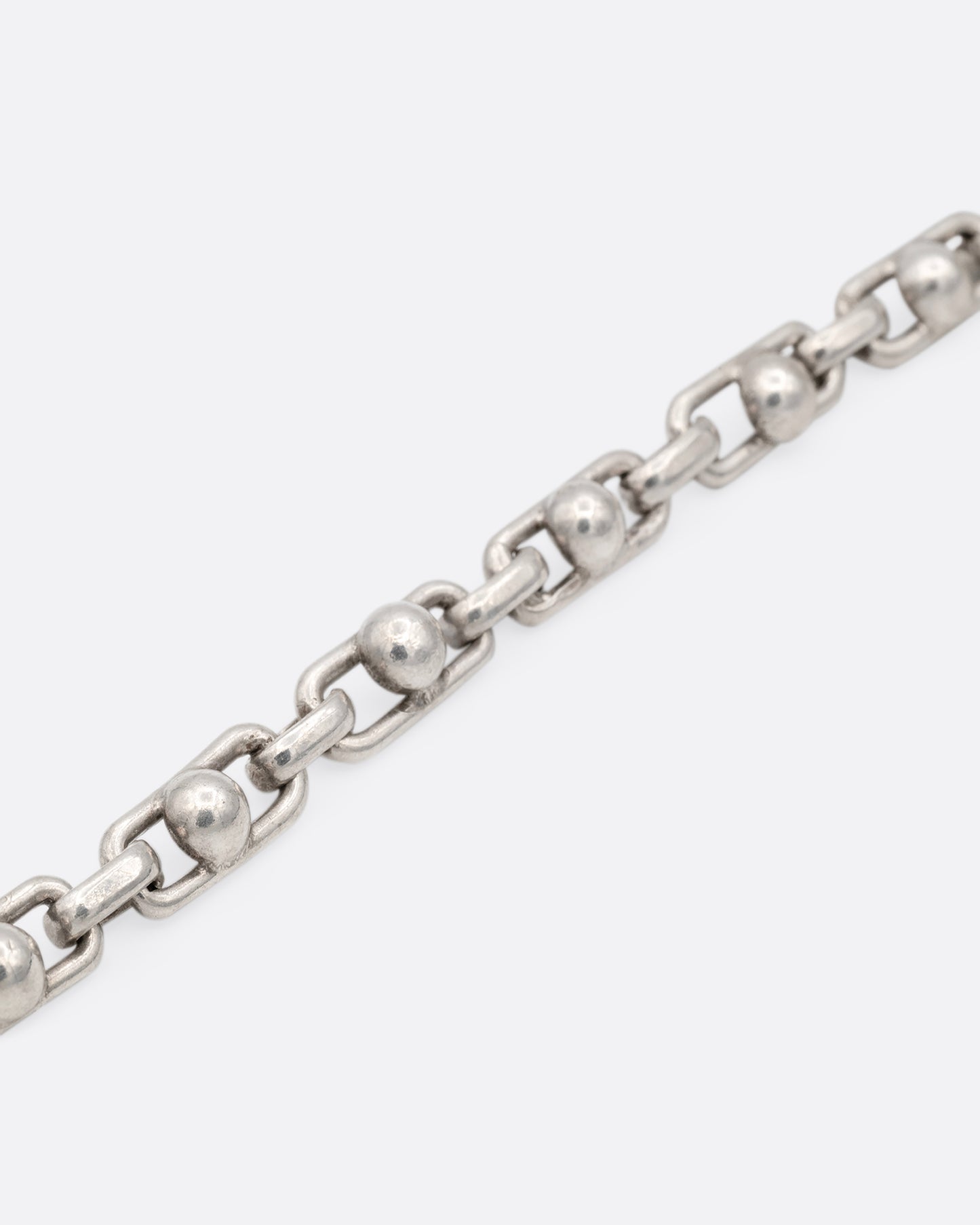 A close up of a silver bracelet with spheres at the center of each link.