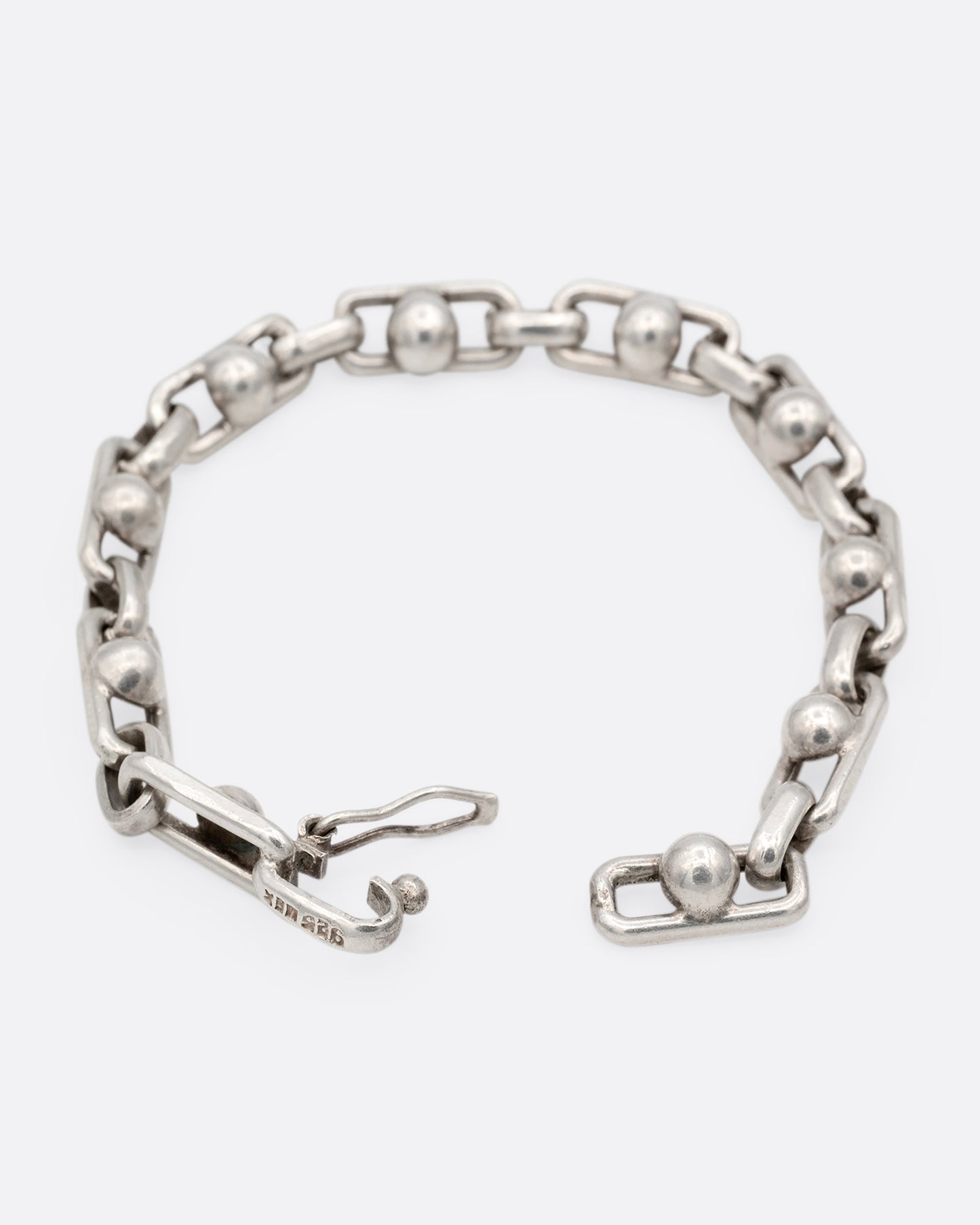 A silver bracelet with spheres at the center of each link. Shown open from the back.