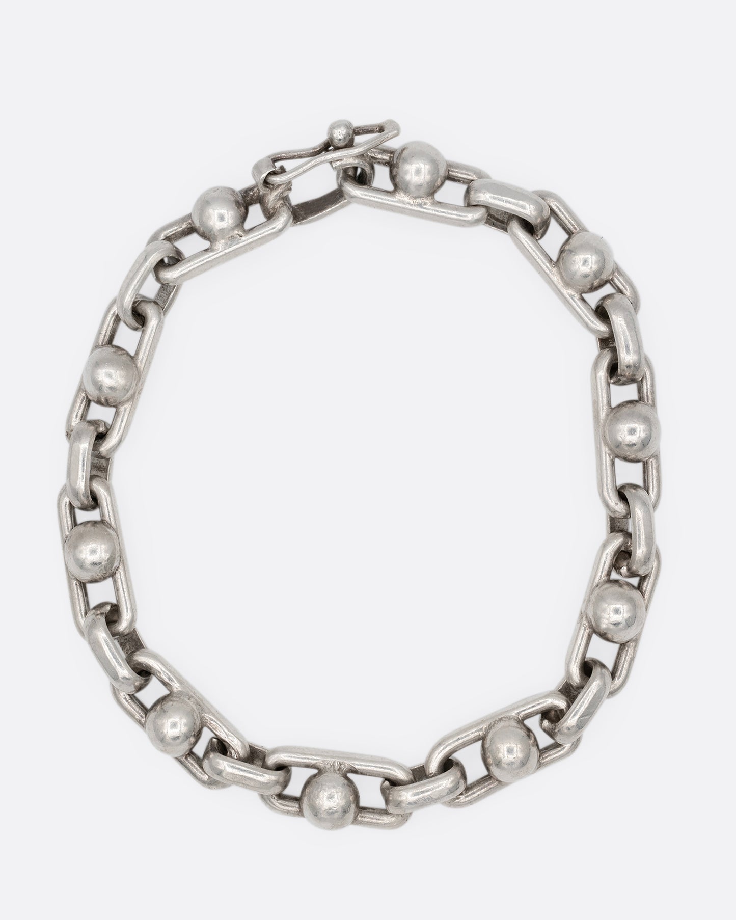 A silver bracelet with spheres at the center of each link. Shown from the front.