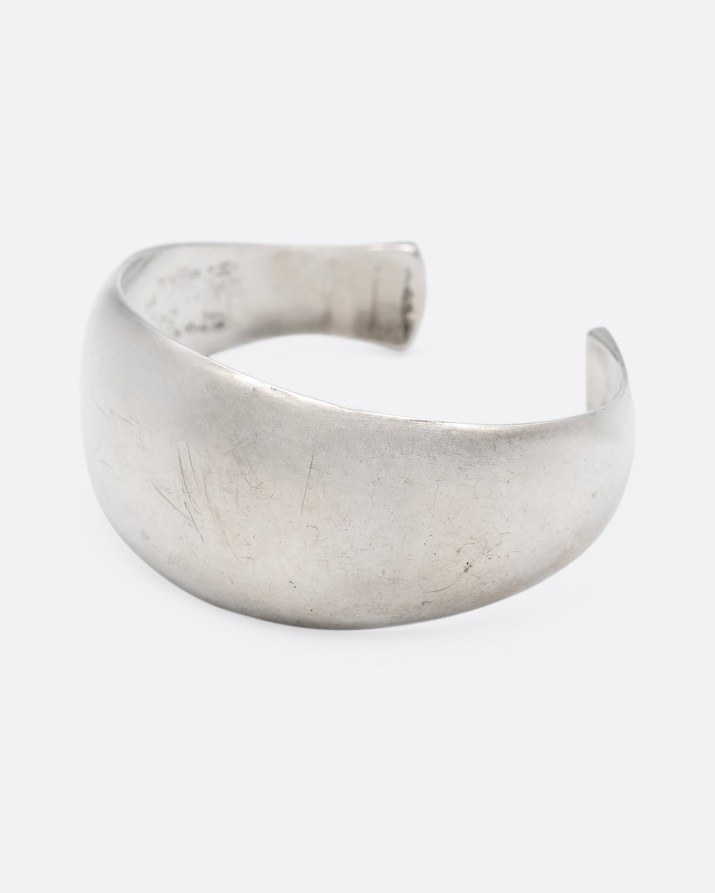 A silver cuff bracelet with smooth edges, shown from the side.