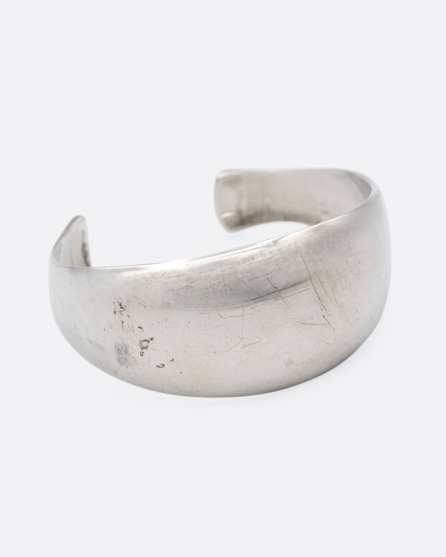 A silver cuff bracelet with smooth edges, shown from the side.
