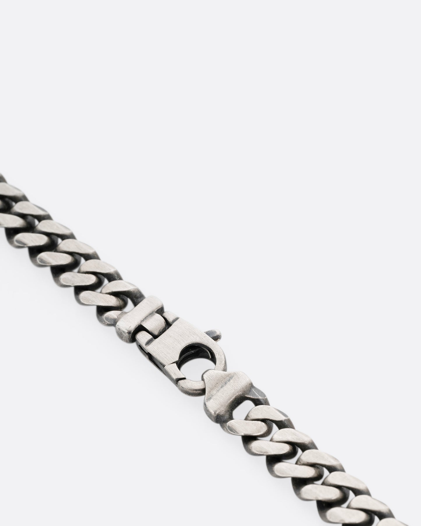 A close up of a silver curb chain necklace.