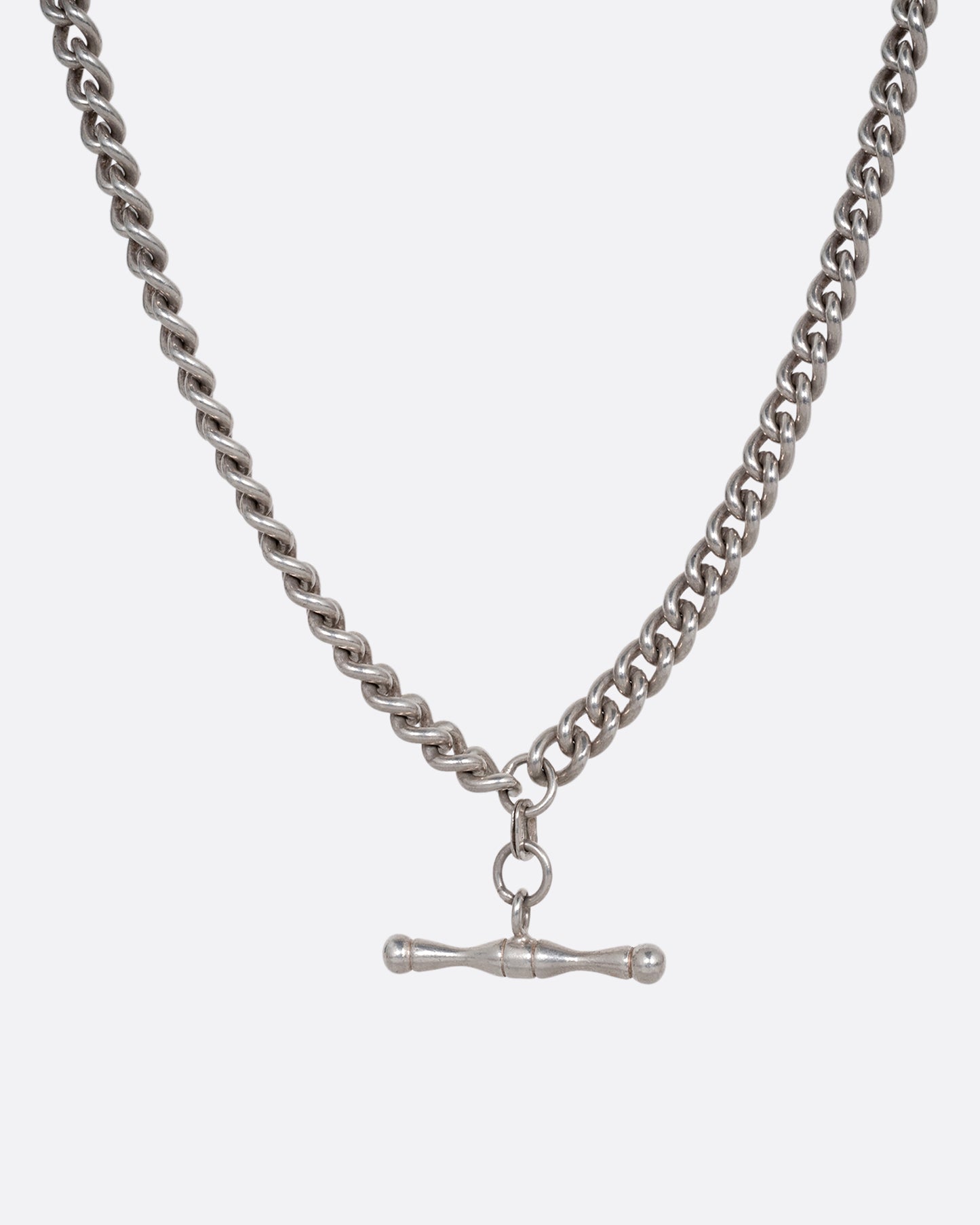 A silver curb chain pocket watch curb chain necklace with a T-bar on one end. Shown from the front.