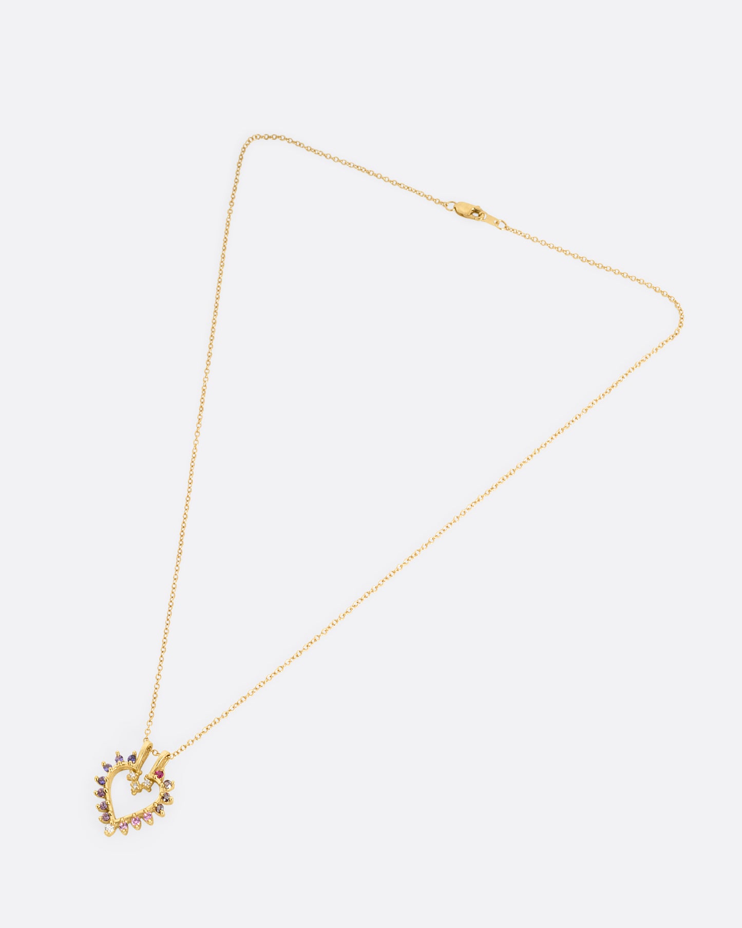 A yellow gold cable chain necklace with a heart shaped pendant with diamonds, rubies, and tourmalines. Shown from the front.