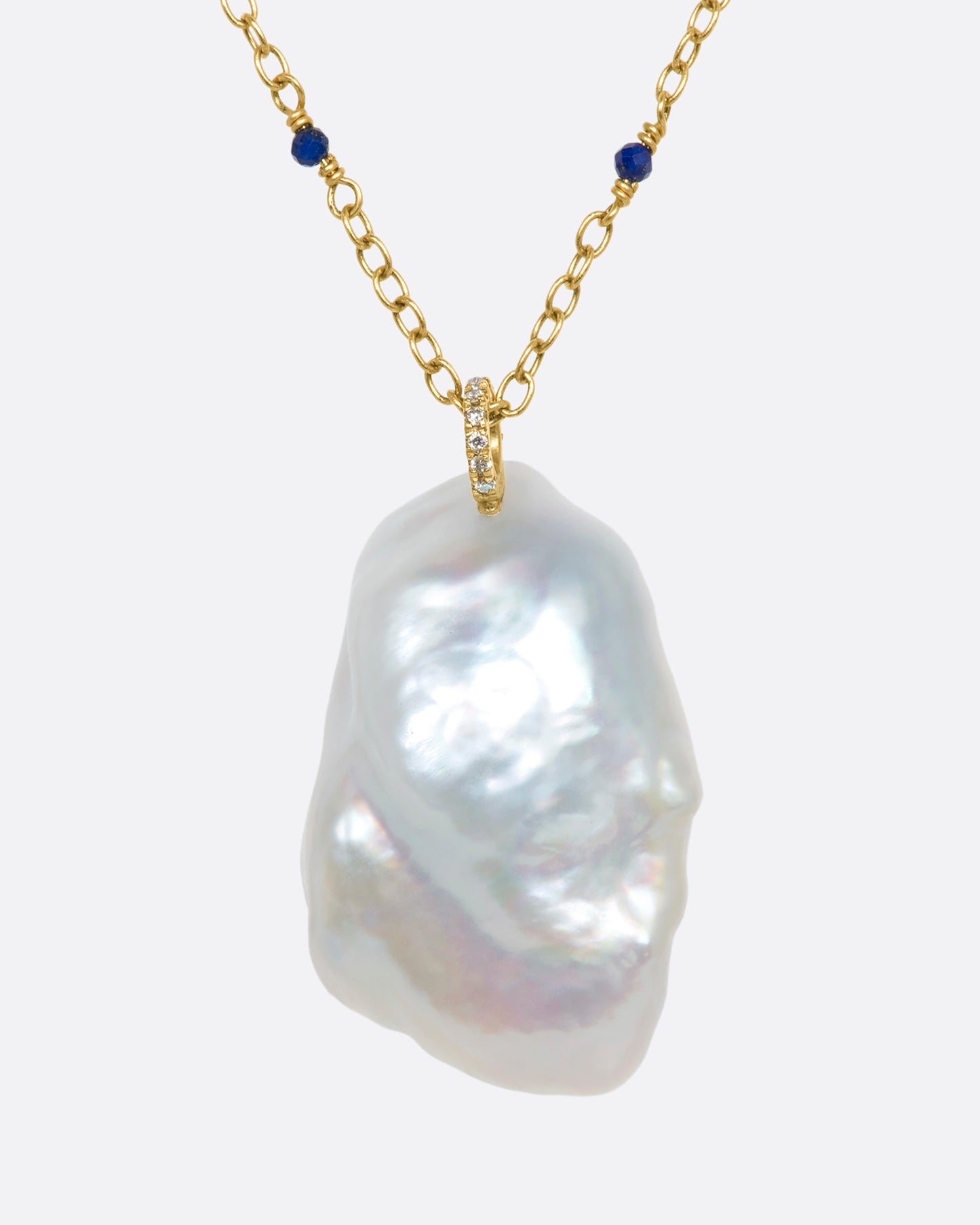 A yellow gold necklace with a hollowed out pearl pendant filled with lapis and 22k gold beads. Shown from the back.