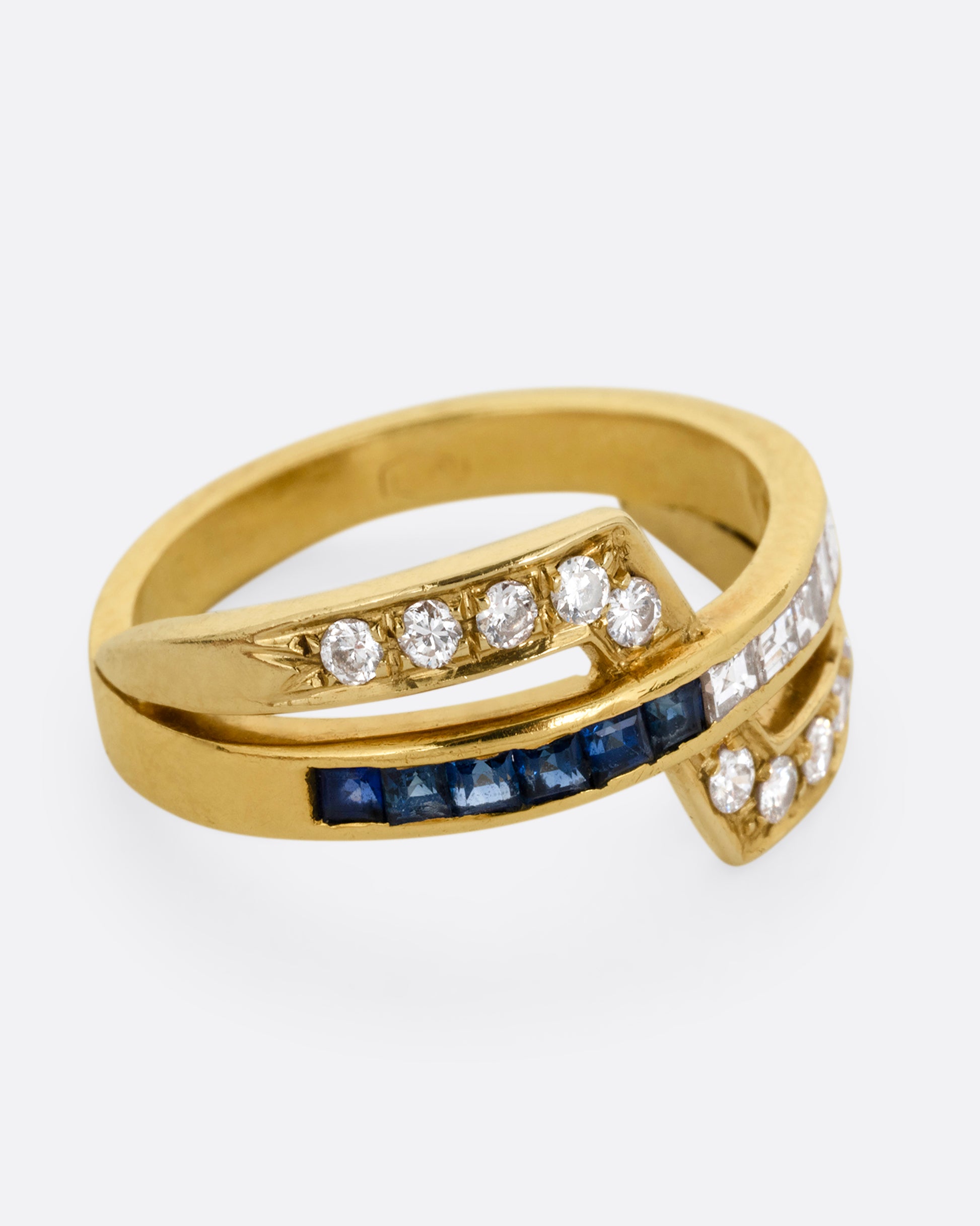 A yellow gold ring with an intersection of diamonds and blue sapphires. Shown from the side.