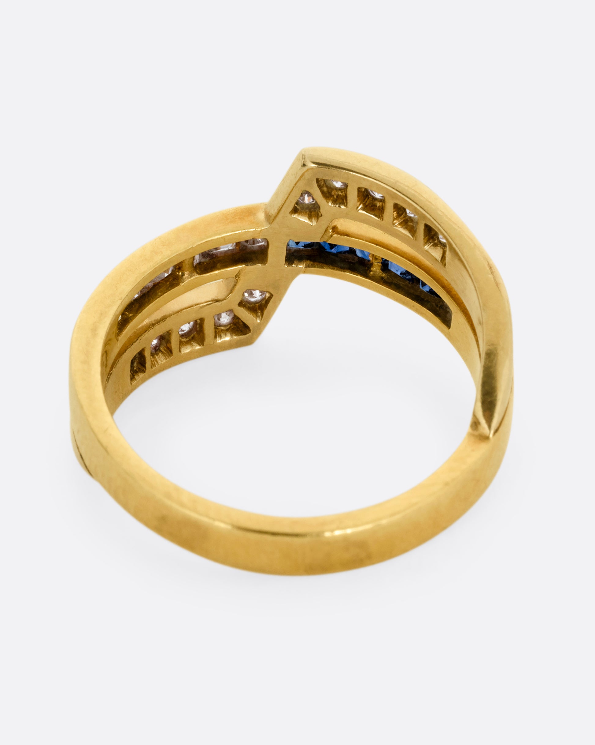 A yellow gold ring with an intersection of diamonds and blue sapphires. Shown from the back.
