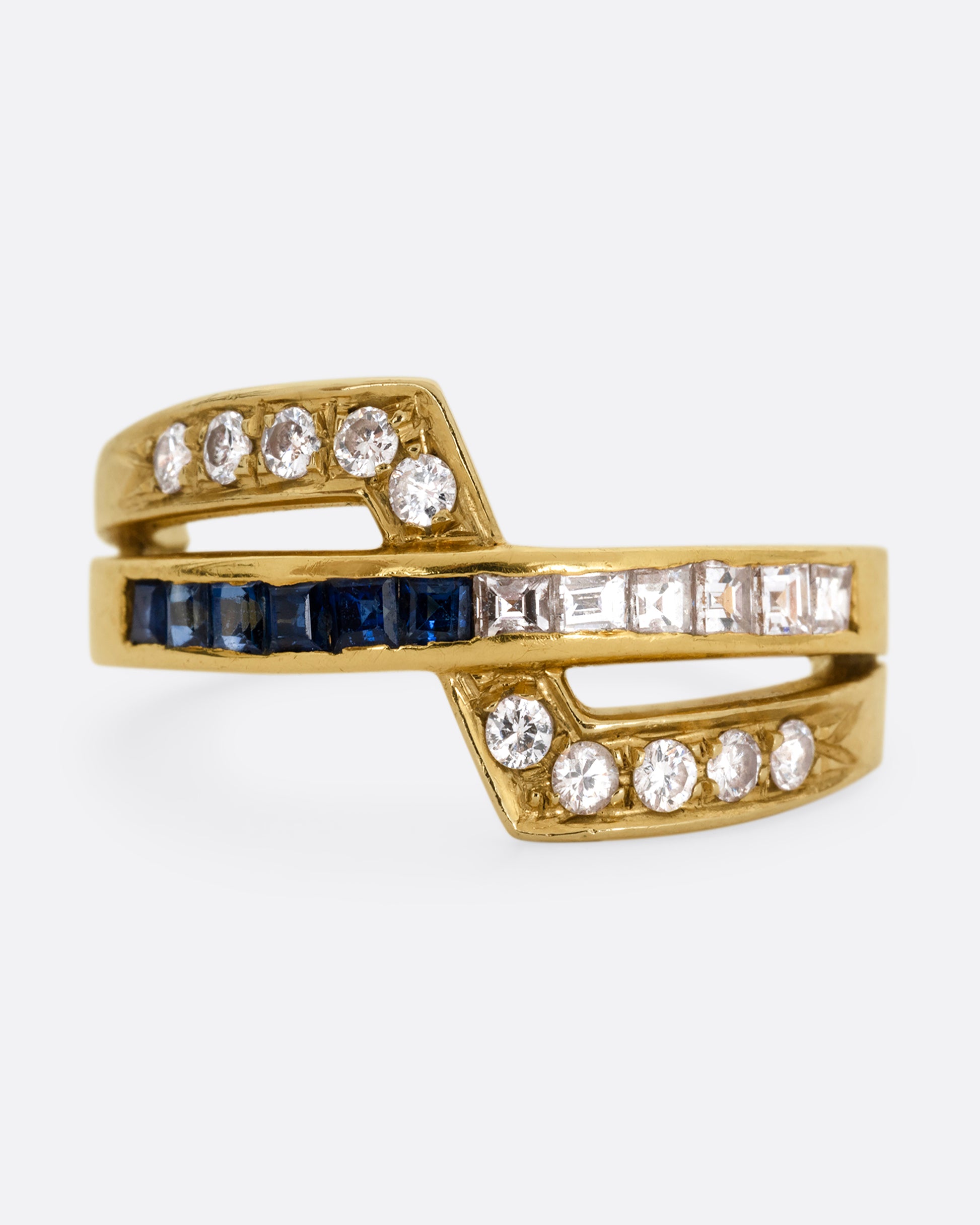 A yellow gold ring with an intersection of diamonds and blue sapphires. Shown from the front.