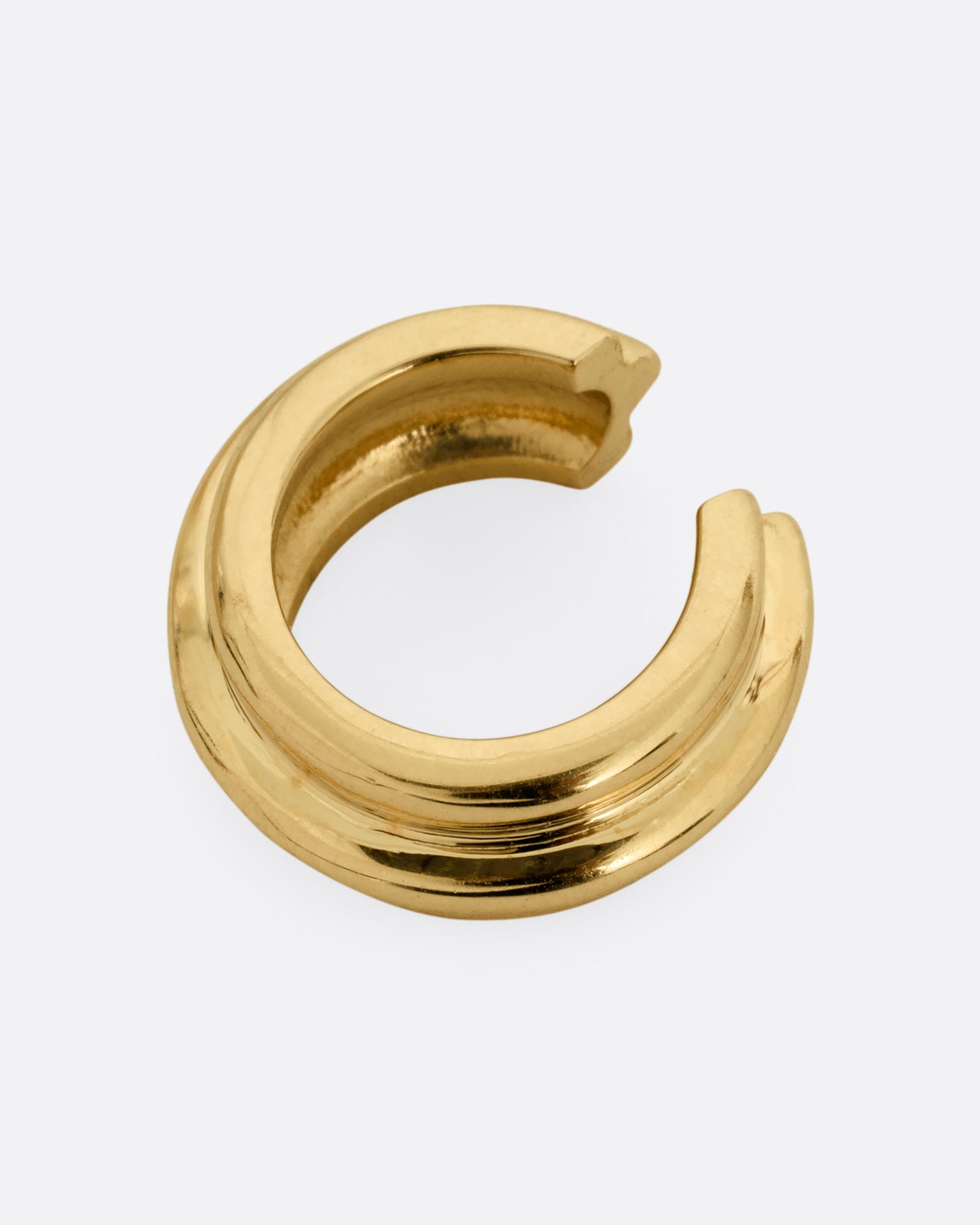 A yellow gold hoop shaped ear cuff shown from the side.