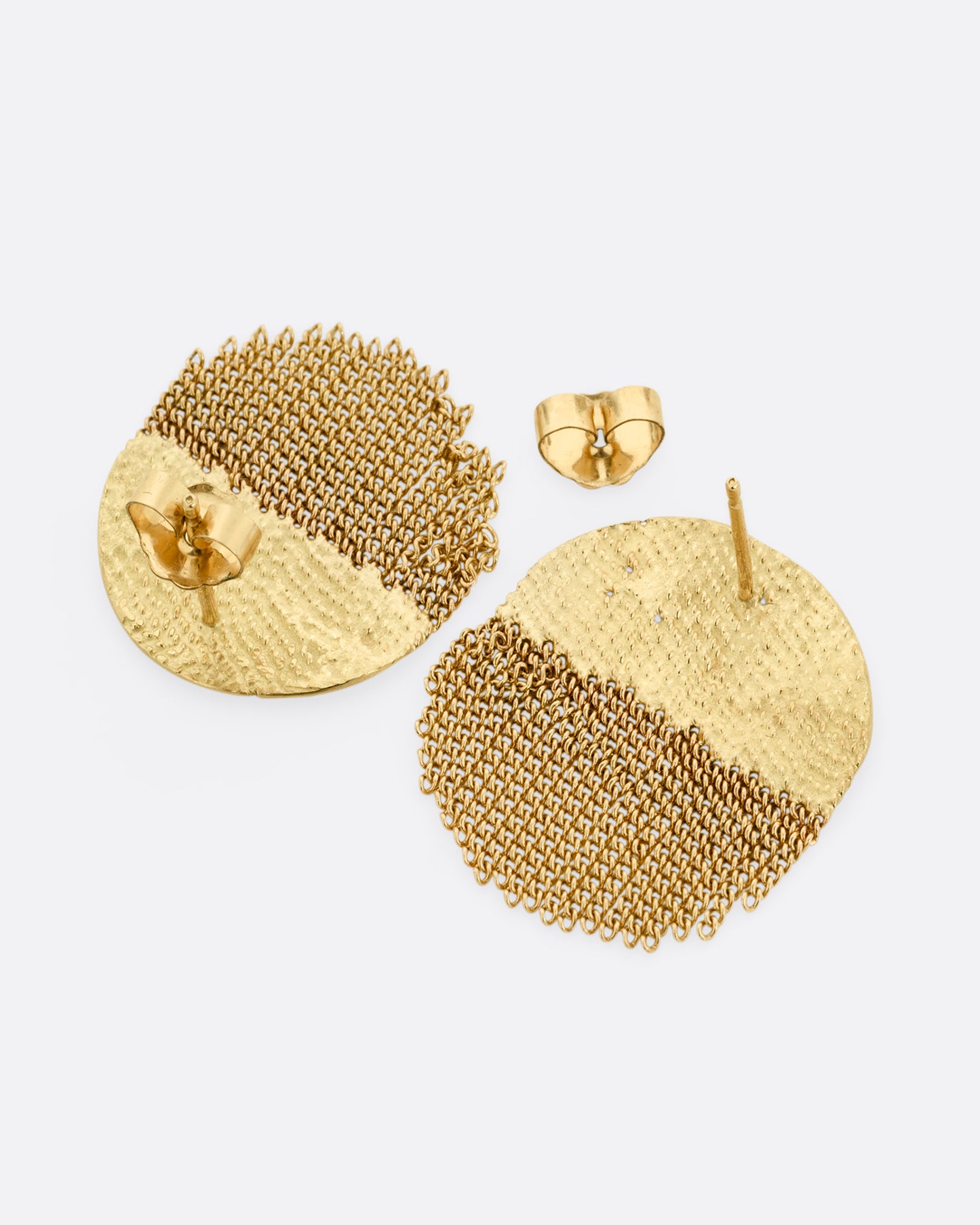 A yellow gold circular stud back earring that's half solid and half fringe chain. Shown laying flat.