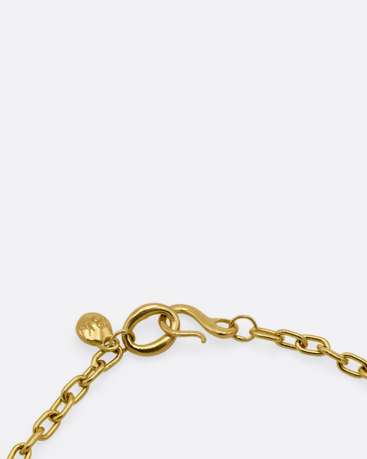 A close up of the clasp of a yellow gold cable chain bracelet with an oval rose cut diamond in a chunky bezel setting.