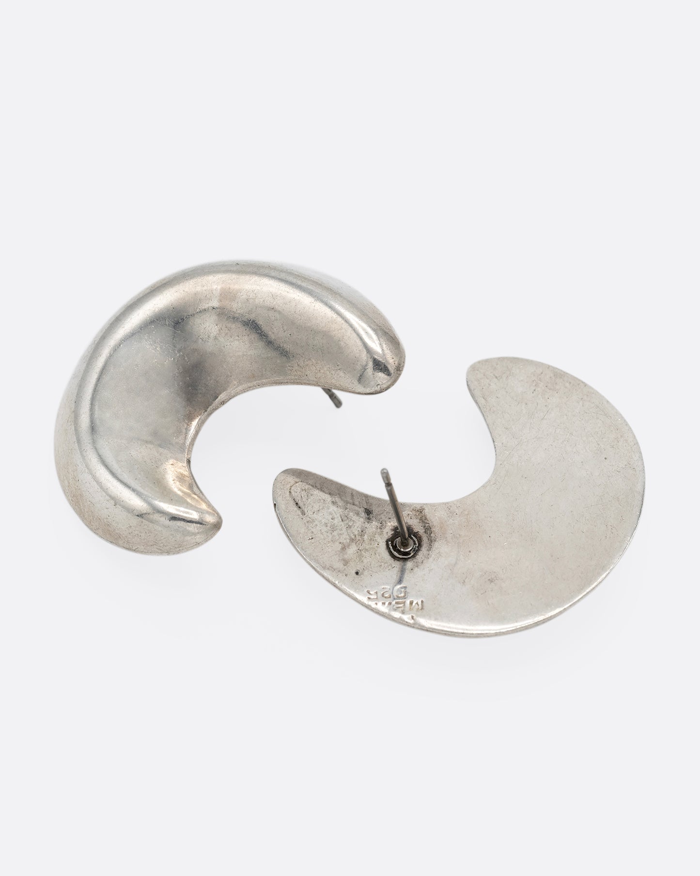 A pair of silver crescent moon-shaped stud earrings, shown lying flat.