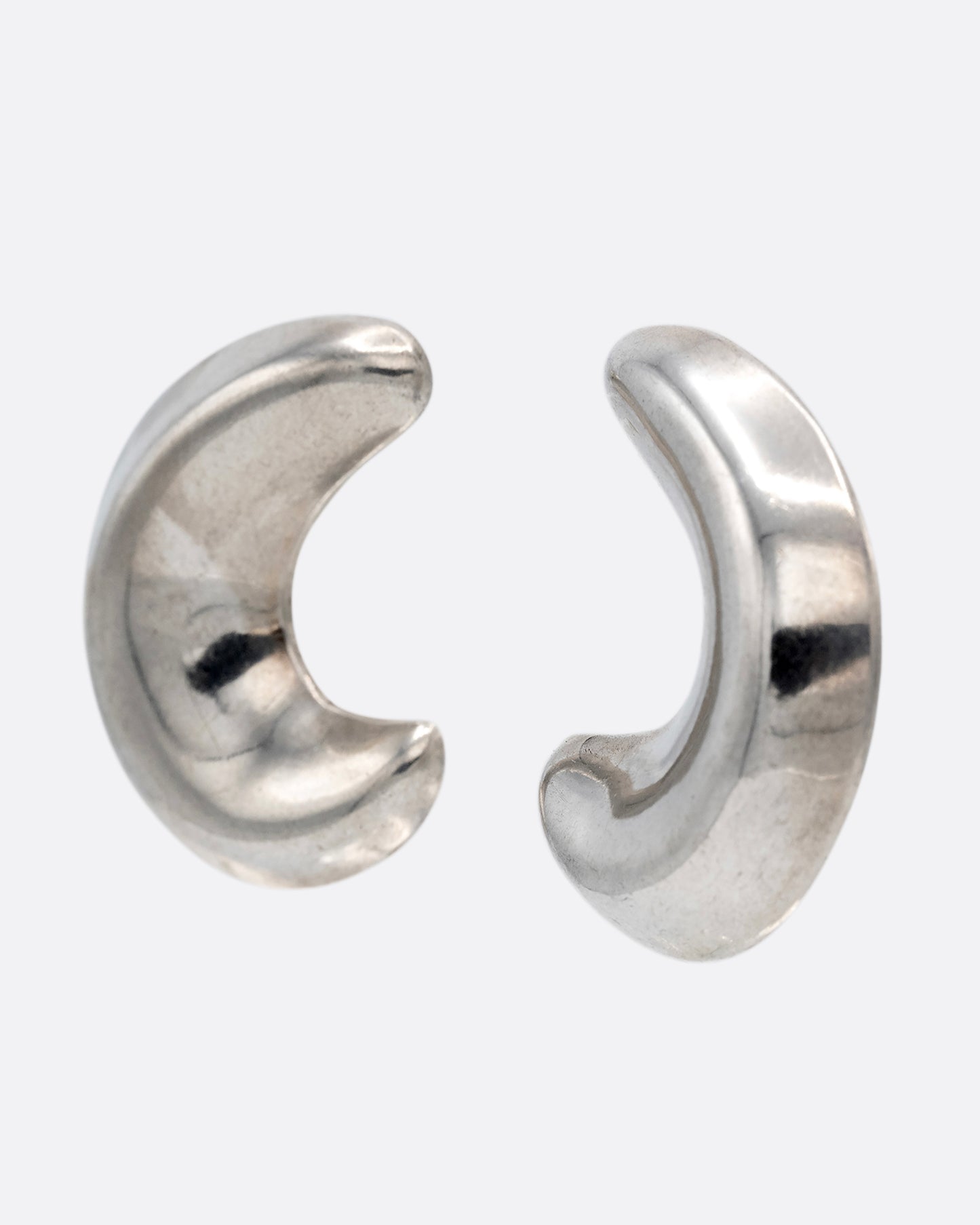 A pair of silver crescent moon-shaped stud earrings, shown from the side.