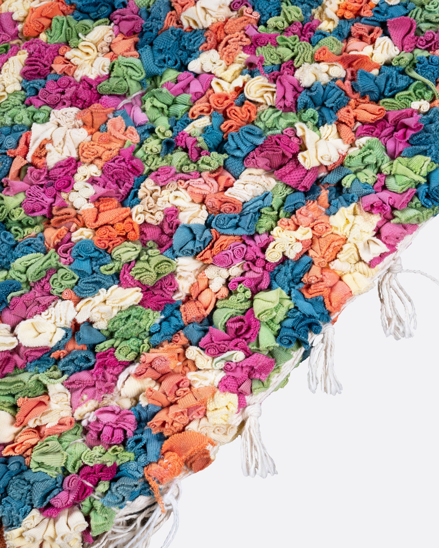 A close up of green, red, orange, and white rectangular rag rug.