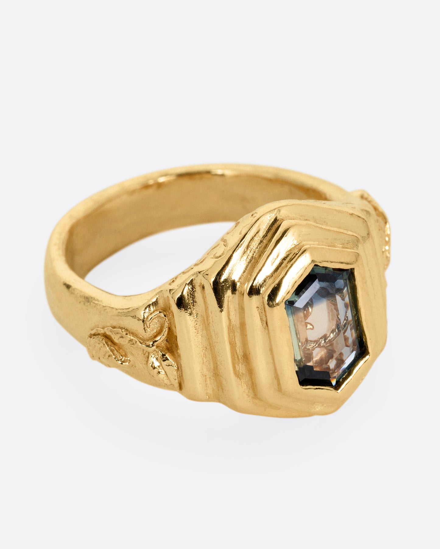 A yellow gold with a stepped center and a portrait cut bicolor tourmaline with a gold tendril that reveals itself through the stone. Shown from the side.