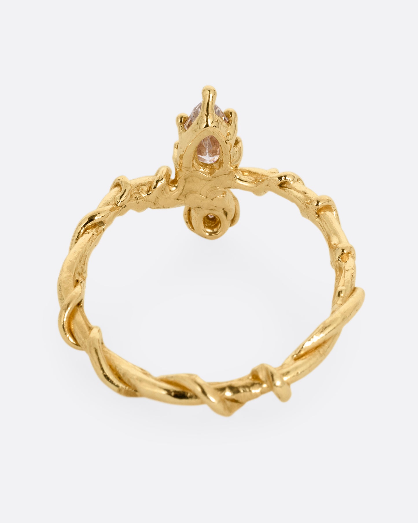 A yellow gold ring with a vine wrapped band and two stacked diamonds, one pear one round. Shown from the back.