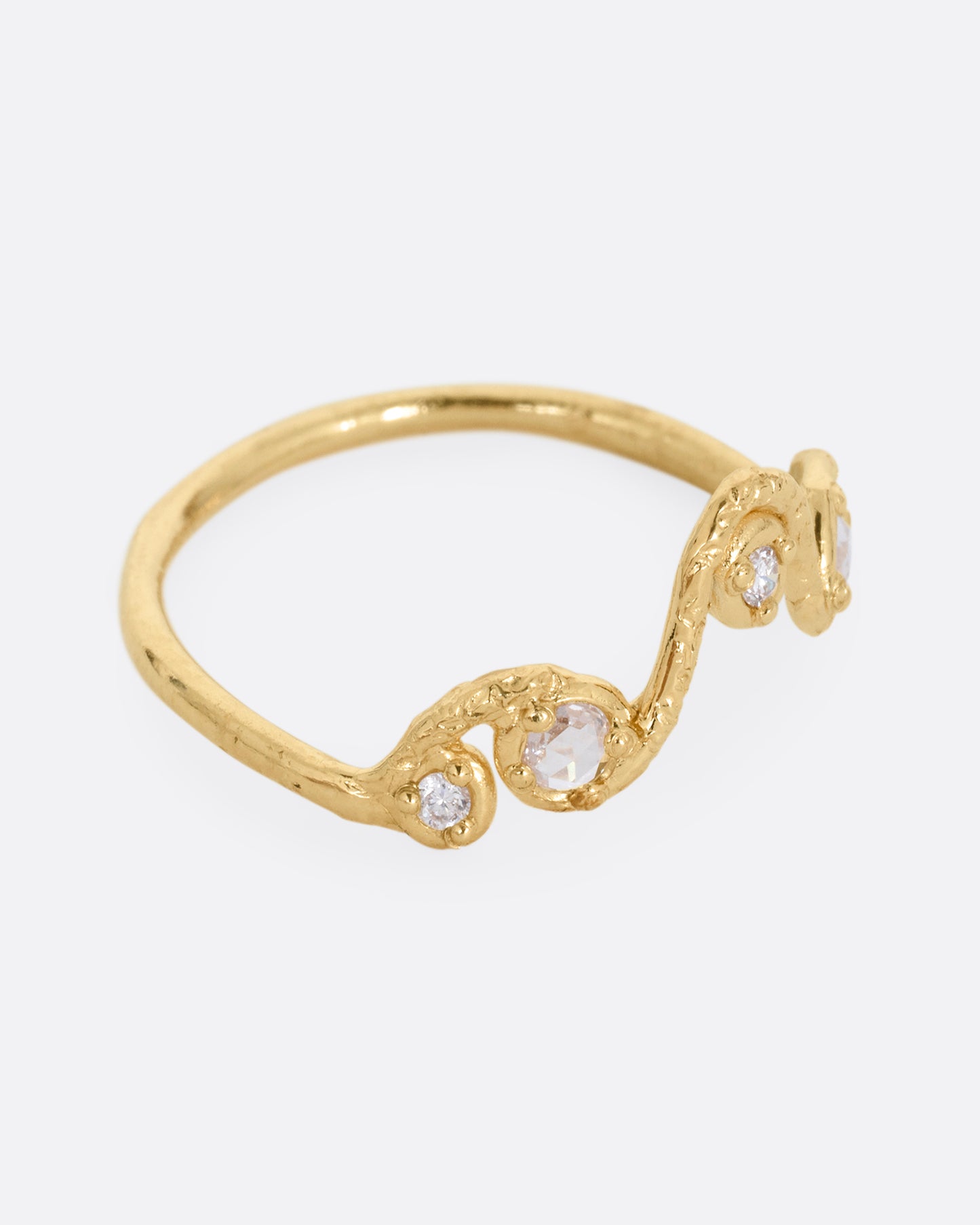 A wavy yellow gold ring with five round diamonds. Shown from the side.