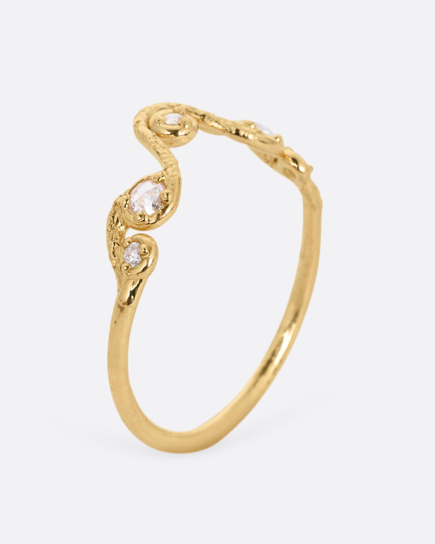 A wavy yellow gold ring with five round diamonds. Shown standing up from the side.