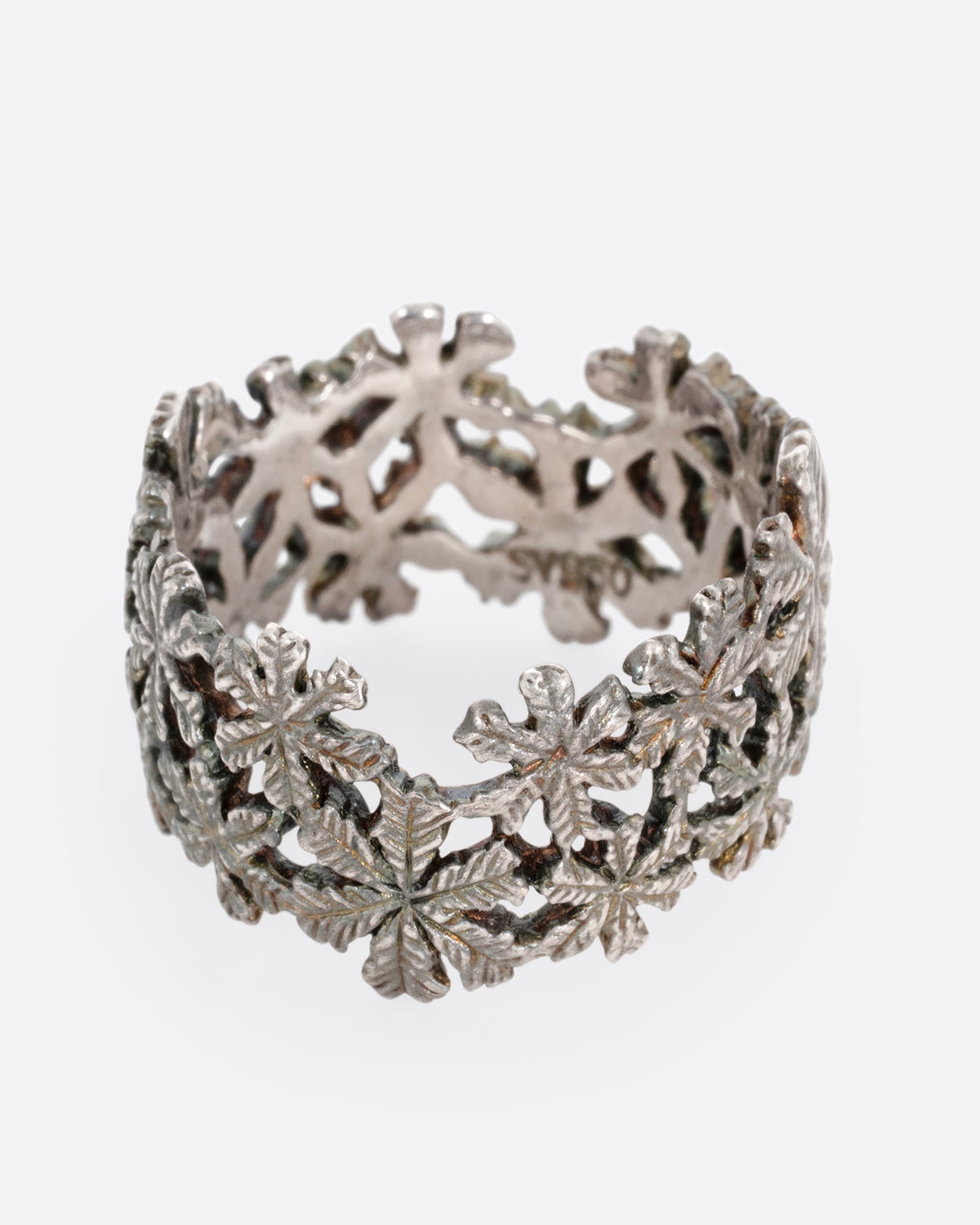 A wide silver ring with a pattern of flowers, shown from the front.