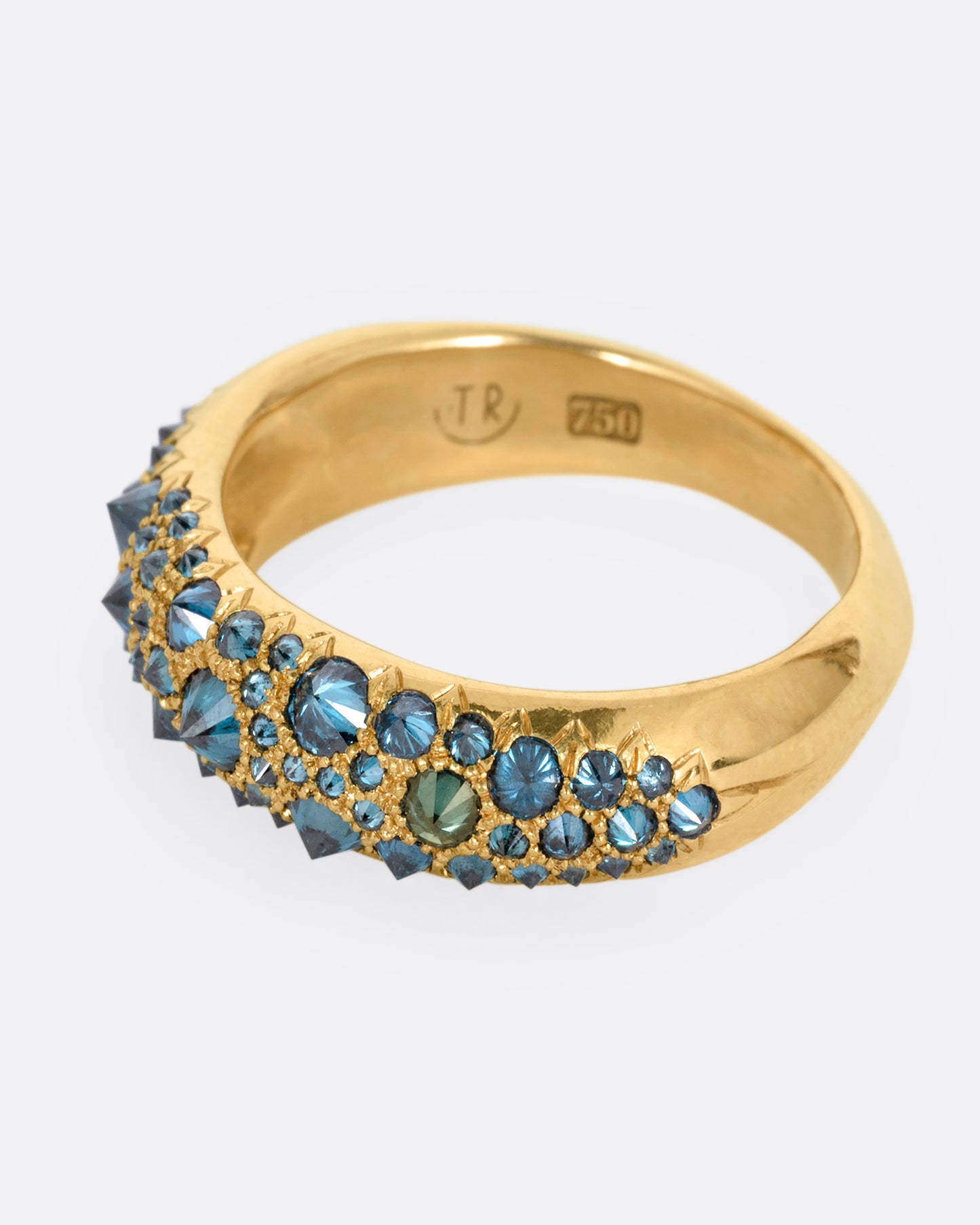A yellow gold ring with reverse set blue diamonds, shown from the side.
