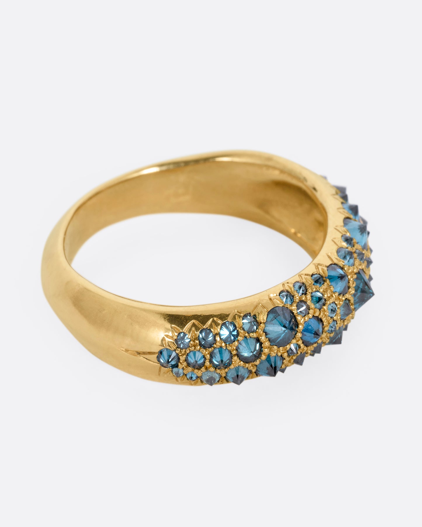 A yellow gold ring with reverse set blue diamonds, shown from the side.