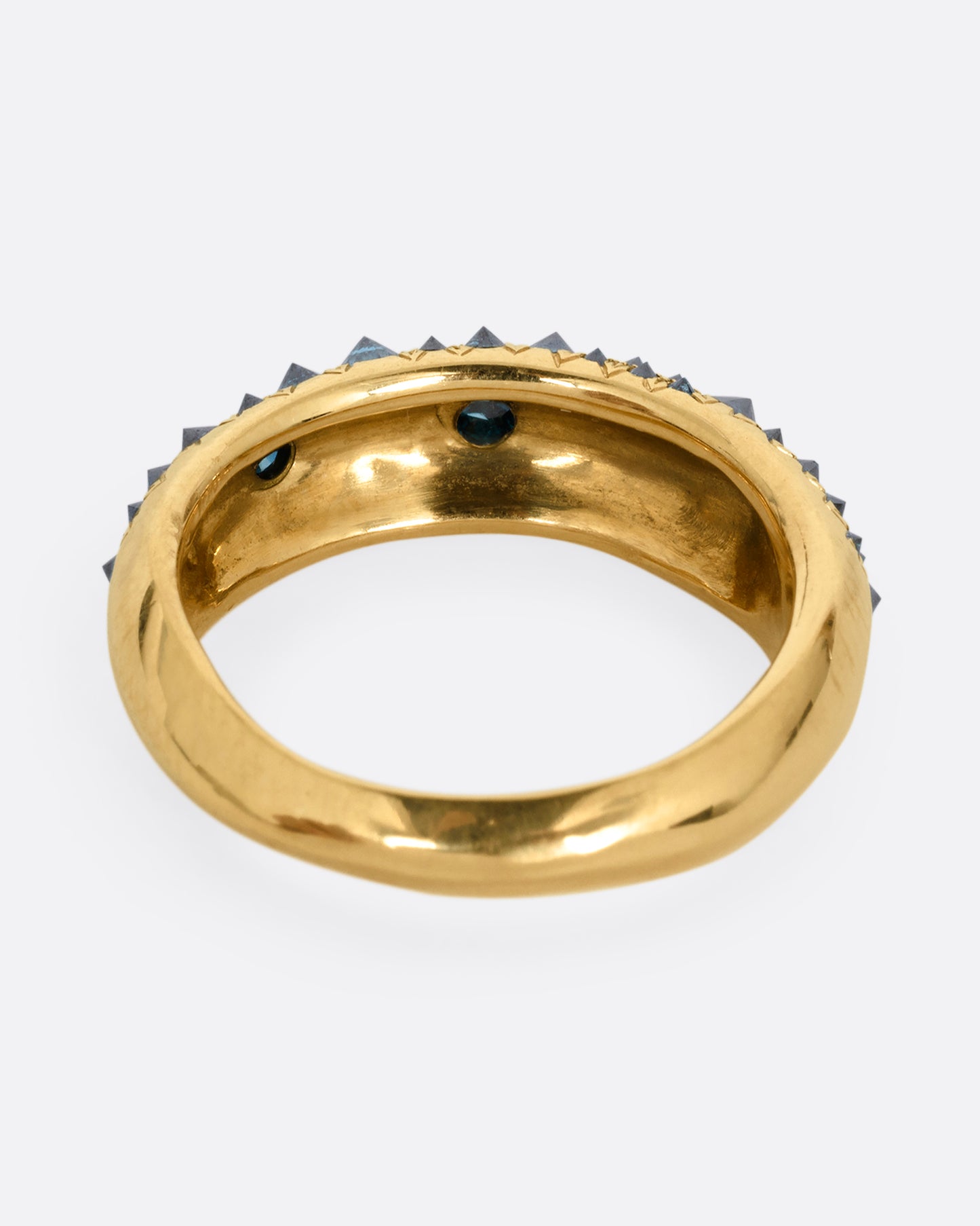 A yellow gold ring with reverse set blue diamonds, shown from the back.
