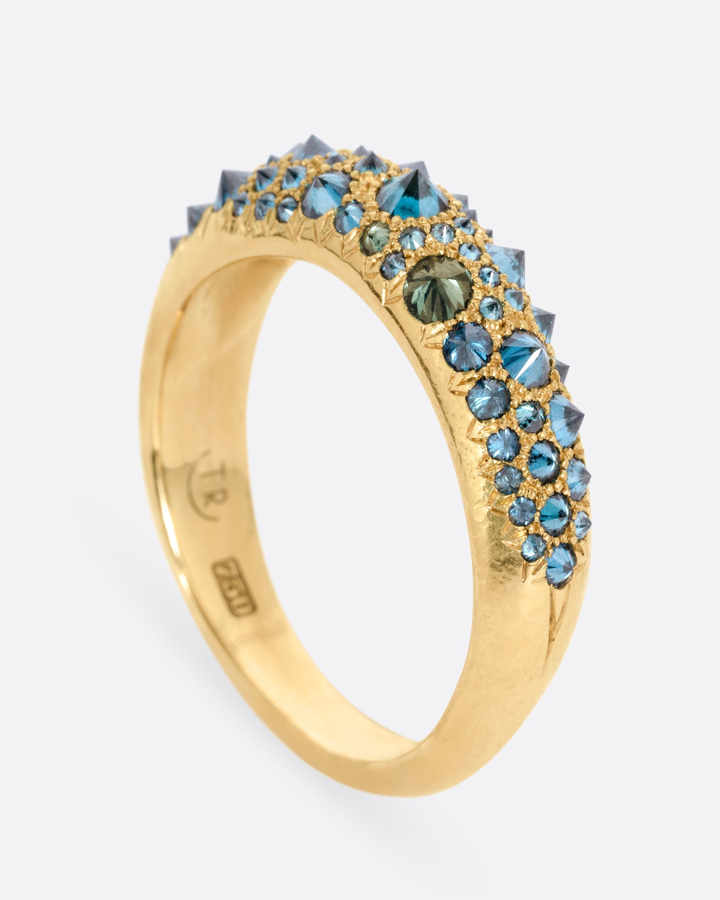 A yellow gold ring with reverse set blue diamonds, shown from the side standing up.