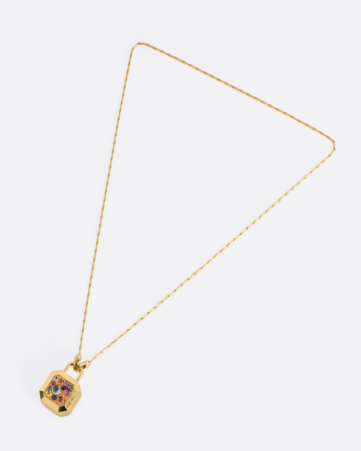 A yellow gold necklace with a padlock shaped locket pendant with multicolored sapphire on its face. Shown from the front.