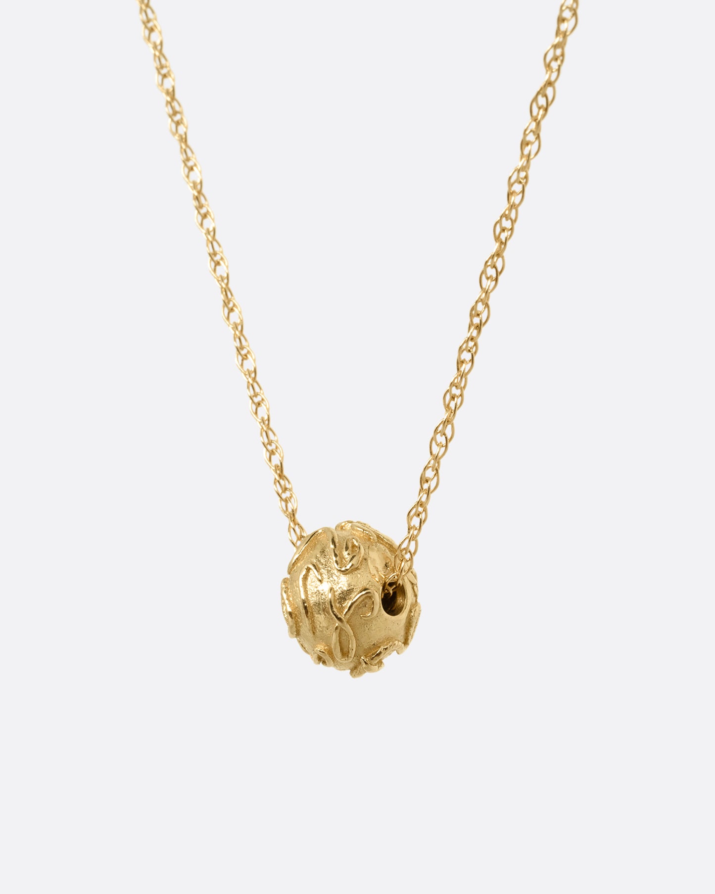A yellow gold cable chain with a textured gold bead, shown from the side.