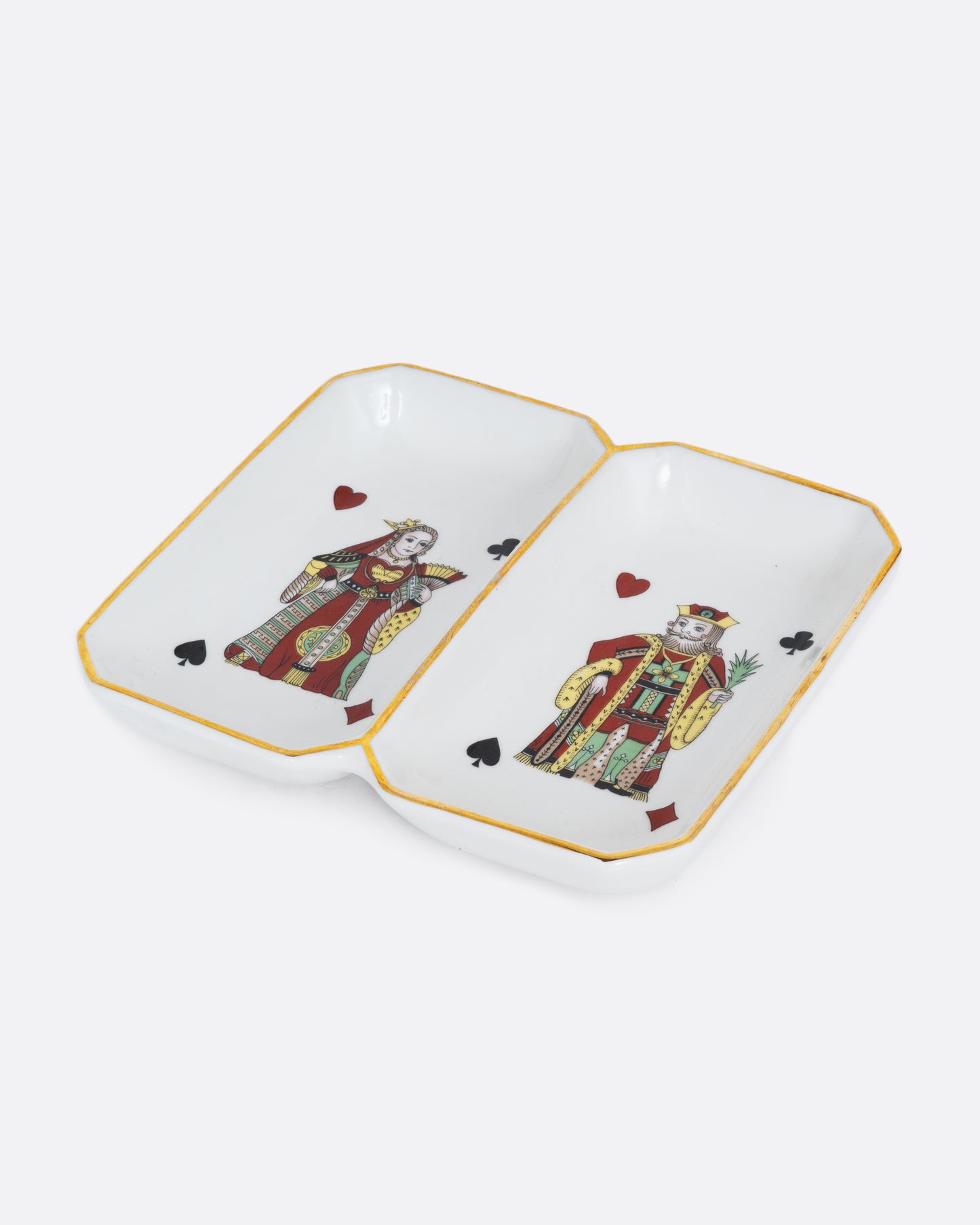 A white dish with gold trim and two playing cards, one a King and the other the Queen. Each has the four card suits on each corner. Shown at an angle from the top.