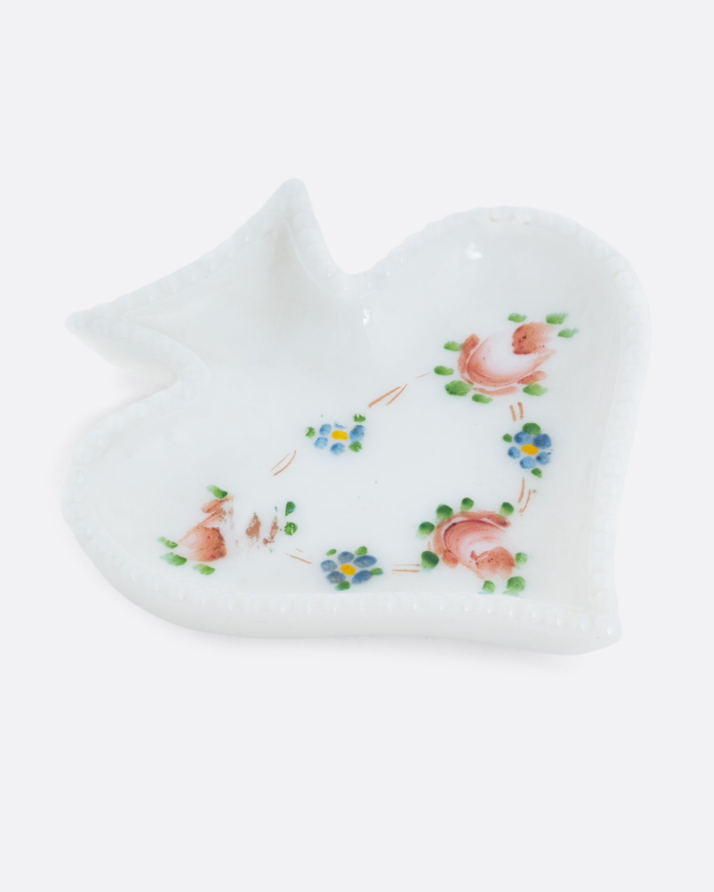 A spade shaped white ceramic dishes shaped like playing card suits with a floral design. Shown at an angle from the top.