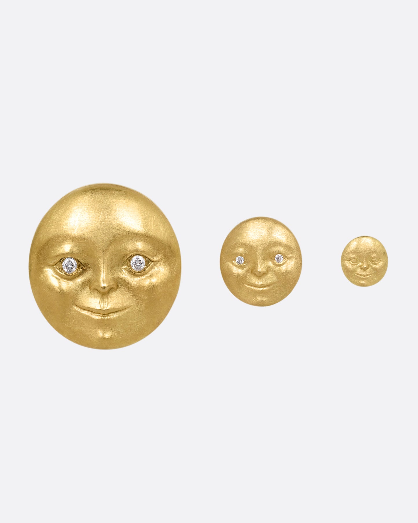 Three yellow gold moon face stud earring with diamond eyes. Shown from largest to smallest from the front.