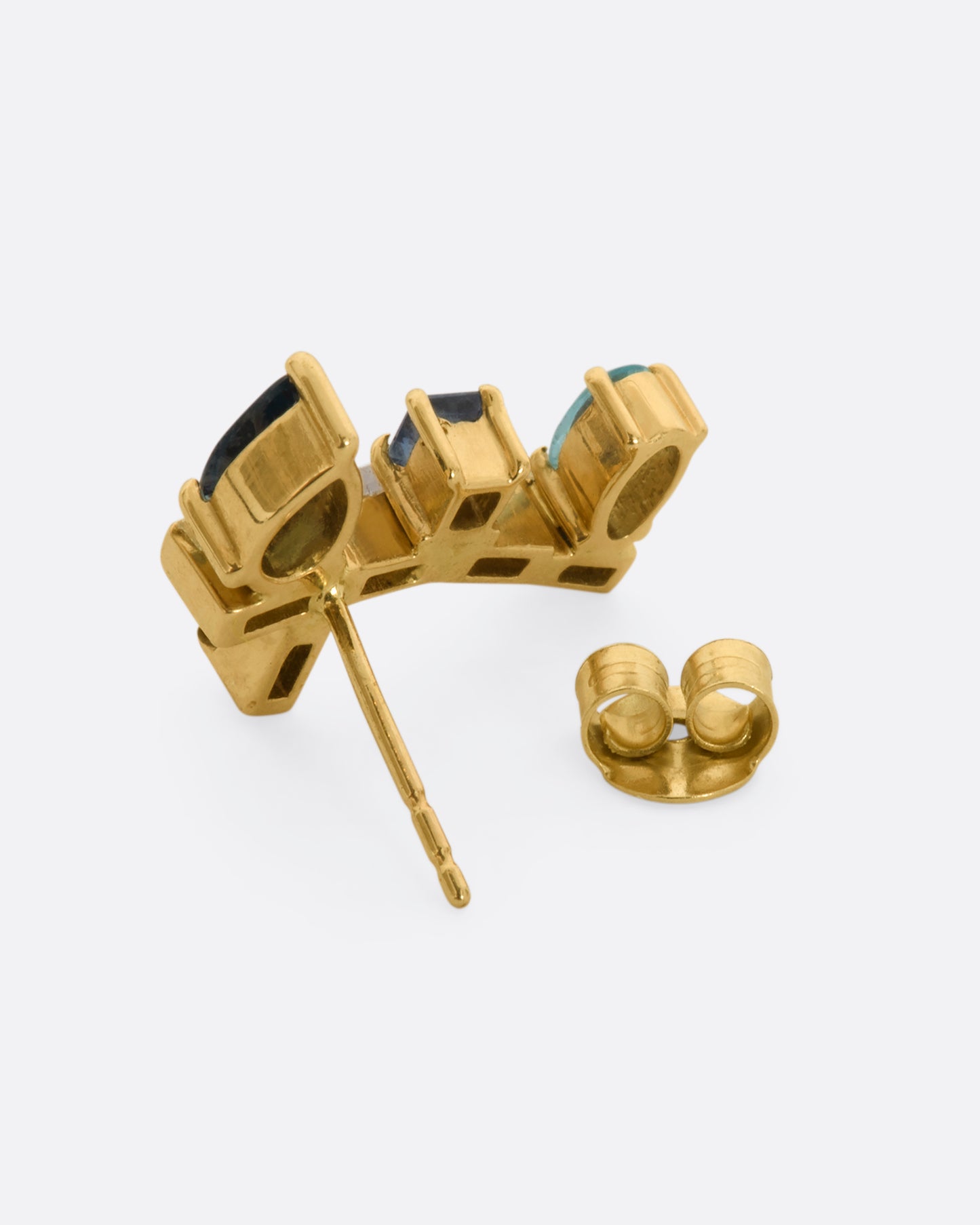 A yellow gold stud earring shaped like a botanical vine made of sapphire, apatite, and diamonds. Shown from the back.