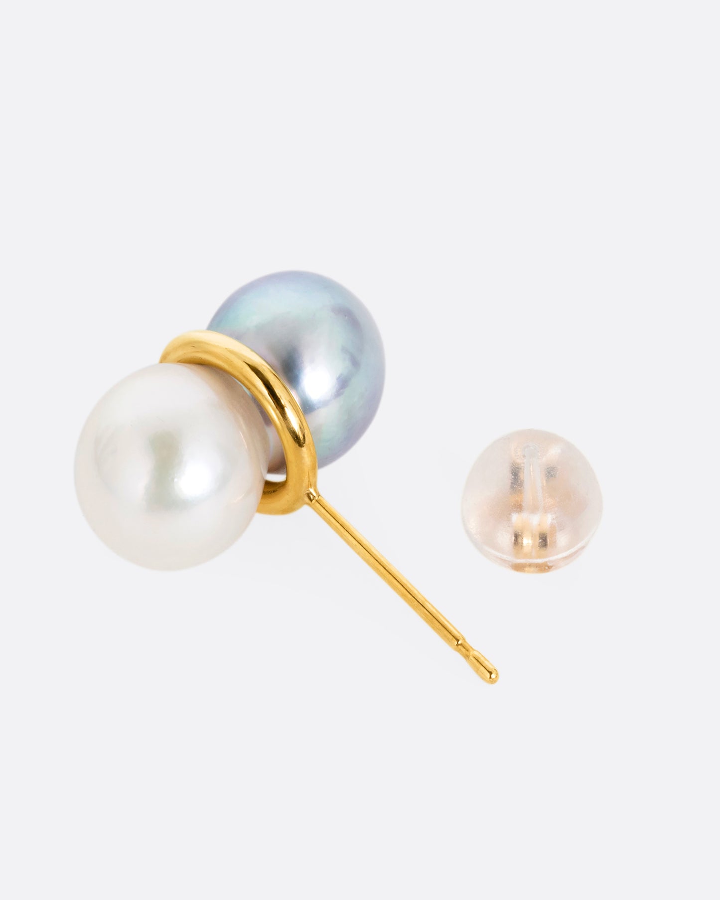 A pearl earring with a gold loop around the middle, shown open lying on its side.