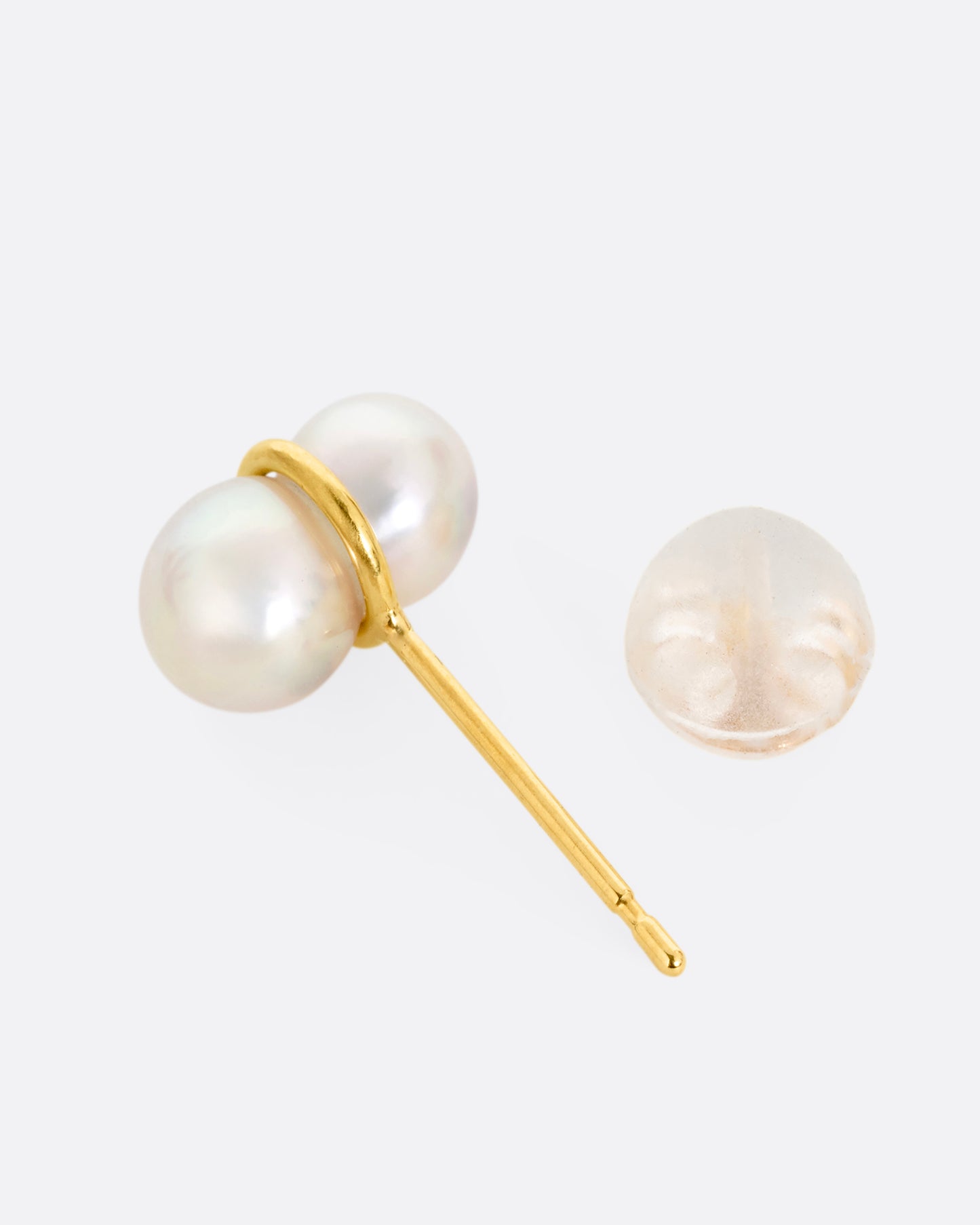 A pearl earring with a gold loop around the middle, shown on its side open.