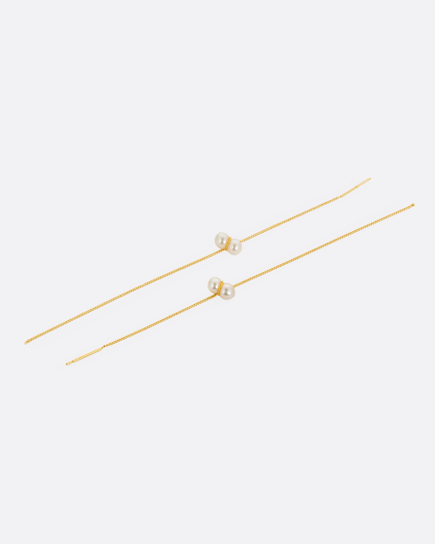 Two yellow gold cable chain threader earrings with white pearls, shown lying flat.
