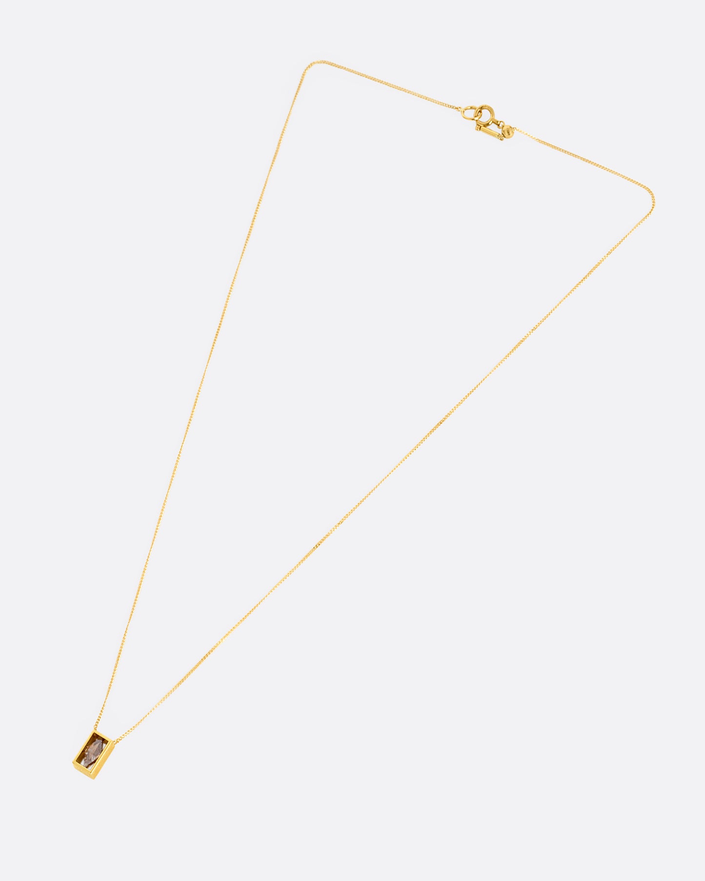A yellow gold cable chain necklace with a rhombus shaped diamond in an open rectangular setting, shown from the front.