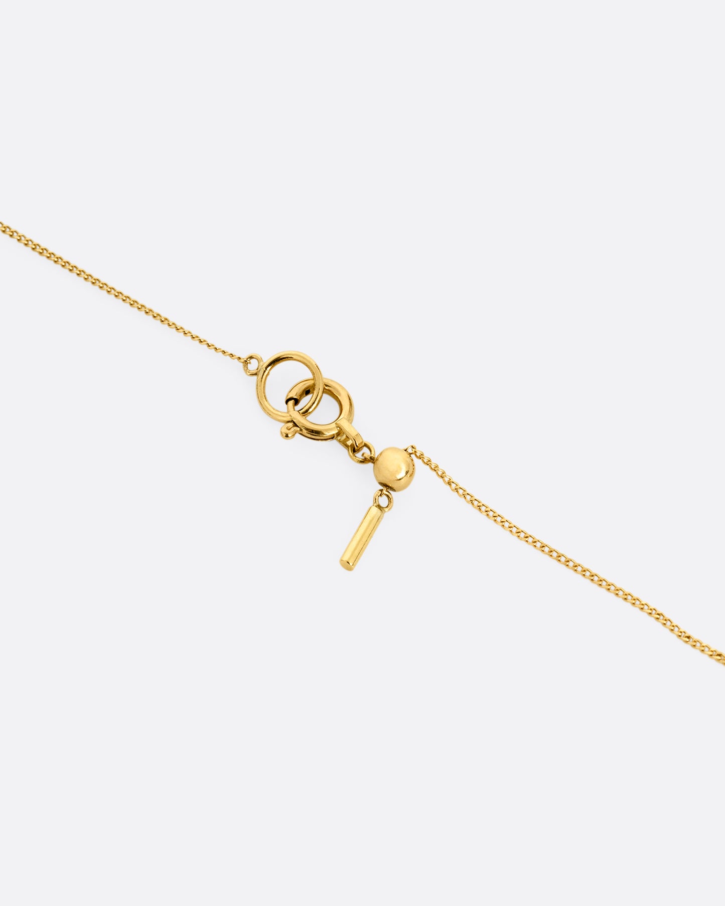 A close up of the clasp of a yellow gold cable chain necklace with a rhombus shaped diamond in an open rectangular setting.