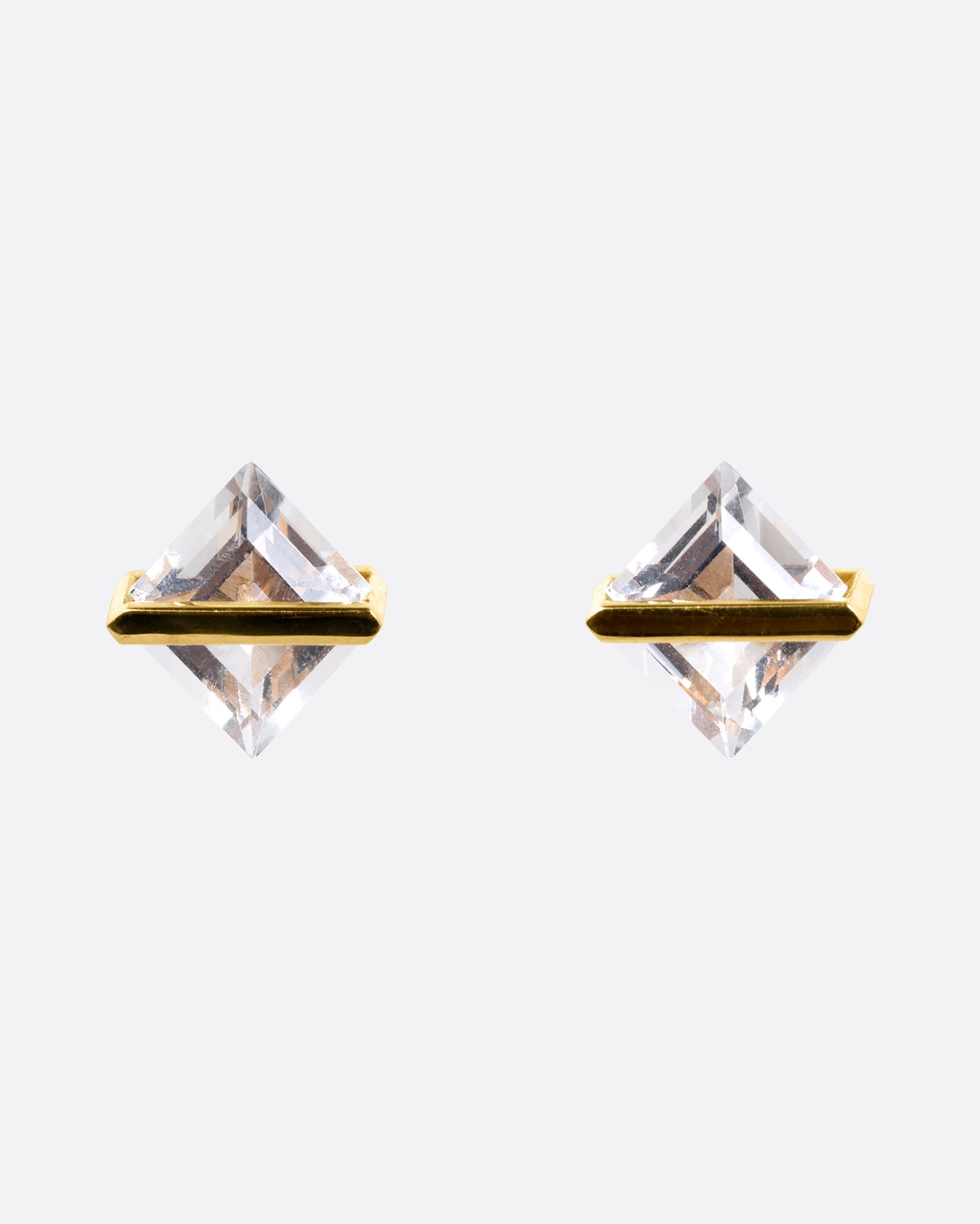 A pair of rhombus shaped quartzes, each in an open yellow gold bar stud earring setting. Shown from the front.